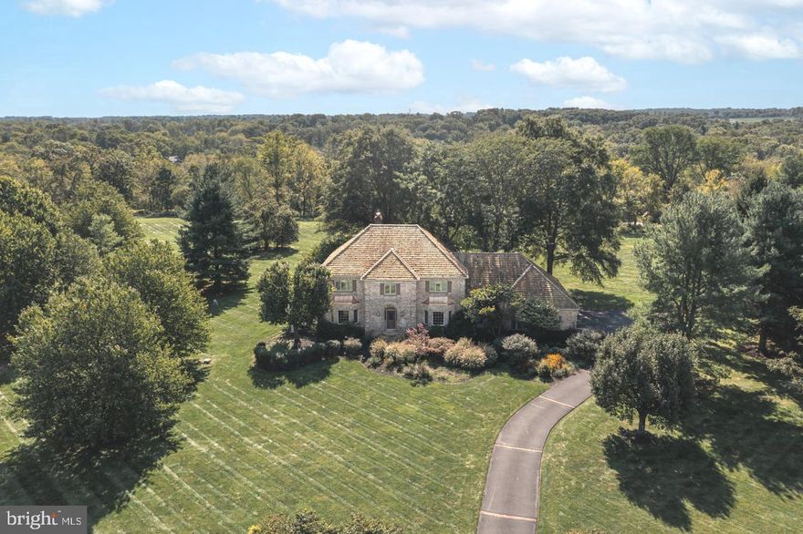 Make your next move to one of Upper Makefield Township’s most alluring and picturesque neighborhoods, Sycamore Farm. Situated in a location perfect for commuting or working from home, this all-brick, classic center hall colonial sits proudly on a home site of over 2.5 acres offering breathtaking hilltop views of Jericho Mountain and the rolling countryside of Bucks County. This custom home was crafted by premier builder George Michael and consists of three levels of living space, extending enough versatility for everyone in the family. Well-maintained and decorated with a neutral palette, this home’s main level features wainscoting draped Formal Living and Dining Rooms, a marble ornamented Foyer with convenient half bath, cozy Family Room decorated with a floor-to-ceiling stone fireplace and built-in wet bar, a Sunroom drenched in natural light from its three walls of windows with access to the fabulous backyard patio, large Kitchen with eat-at island, granite countertops and new premium appliances, Mud Room with neighboring half bath, and a large Study adorned with a fireplace. Access the second level from the front curved staircase to find a sizeable Primary Suite with a desirable, roomy walk-in closet with organization and a luxurious spa-like full bath which connects to laundry room with pocket door. Three generous-sized bedrooms are also located on this level; one being an En-Suite along with a centrally positioned hallway full bath showcasing a dual sink vanity. Downstairs, the finished lower level offers amazing entertainment and gathering space with its billiard, ping pong and movie viewing areas including a custom-built bar with wine refrigerator and ample storage. Outside, relax in your private retreat on the large patio offering long-distance views surrounded by mature landscape, multiple seating areas and providing plenty of space to play. Additional amenities include an attached 3-car garage, dentil molding, hardwood flooring, New upstairs windows, water proofing system in basement, central vac system, geothermal heating/cooling, house generator and more. Whether indoors or outdoors, this home lends itself to entertainment and provides many places to spend quality time enjoying visits with family and friends. Located in Award-winning Council Rock School District - Sol Feinstone elementary and minutes to the I-295 corridor and the charming towns of Newtown, New Hope and Washington Crossing.