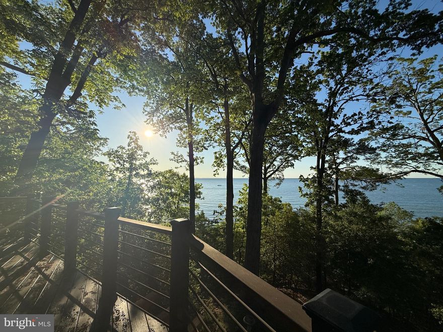 Welcome to a rare offering on the Chesapeake Bay—this architect-designed 1979 Acorn Deck House seamlessly blends timeless mid-century modern design with breathtaking waterfront living. Privately tucked among the trees, this exceptional split entrance home showcases signature post-and-beam construction, rich natural wood finishes, and dramatic walls of glass that frame panoramic bay views from both levels and almost every room.  

Step inside to a light-filled main level where soaring cathedral ceilings and floor-to-ceiling windows create a stunning connection to the water. Family room features a wood burning brick fireplace and flows effortlessly into the updated kitchen and dining area complete with Corian countertops, center island, and heated floors—perfect for gathering and entertaining. A sunroom and expansive wraparound deck extend your living space outdoors, offering front-row seats to ever-changing Chesapeake Bay vistas.

The primary suite is a true retreat, featuring private deck access, sweeping water views, and a beautifully updated bath with jetted tub, walk-in shower, and heated ceramic tile floors. A renovated guest half bath completes the main level.

The lower level is equally impressive, filled with natural light and designed for both relaxation and functionality. Enjoy a spacious rec room with a second brick fireplace, direct access to the lower-level deck, two additional bedrooms, a fully renovated bath, and generous storage areas.

Outside, a private walkway leads to your own sandy beach along the Chesapeake Bay—an incredible extension of this already remarkable property. A two-car garage with direct access to the home adds convenience to this one-of-a-kind property. 
This is more than a home—it’s a lifestyle defined by architecture, privacy, and unparalleled waterfront views.