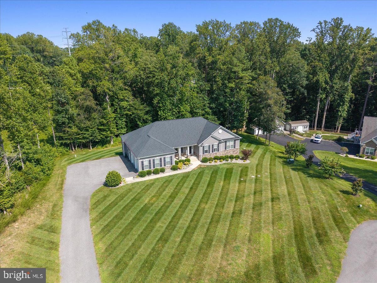 A rare find in Oakland Hall, this one-level Glenwood 2 model is calling your name. Built with Quality Built Homes in 2018 and ENERGY STAR QUALIFIED, this home combines thoughtful, high-end finishes, and quality craftsmanship in one of Calvert County’s most desirable communities. The open-concept layout seamlessly connects the dining room, living room, and kitchen, creating a spacious and inviting main living area. The kitchen features a tile backsplash, granite countertops, a huge island for prepping/serving. The best part though? A large hidden pantry that you have only dreamed of, tucked behind the cabinetry for added storage! Just off the kitchen, take in the wooded backyard views from your trex deck with sleek black railing and a yard that could fit a pool! Engineered hardwood flooring runs throughout the main level and only 2 of the rooms have carpet. A functional mudroom sits just off the 2.5-car sideload garage with epoxy flooring. The primary suite includes the classic QBH walk-in tiled shower with a glass door, dual vanities, and a walk-in closet. Two additional bedrooms and a second full bath are tucked away along with a spacious linen closet and separate laundry room, offering privacy and convenience. Thoughtful finishes like a sliding barn door leading into the primary suite bathroom and landscape lighting with permanent accent lights around the roofline adds charm and character. The curb appeal shines with stone accent columns, rock beds, and a welcoming front porch. Enjoy one of the flatter lots in the community, with a walkout basement - ideal for both entertaining and daily living. As a resident of Oakland Hall, you’ll enjoy access to community amenities including a clubhouse, swimming pool, sidewalks, and street lighting - creating a neighborhood that feels as inviting as the home itself.
