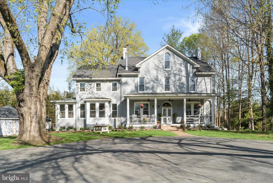 Welcome to 4310 Buckeystown Pike, an incredible estate showcasing a grand all-brick Victorian set behind a gated entrance and framed by mature trees and a sweeping circular drive. Rich in historic charm, this remarkable home blends original architectural details such as the front and rear doors, arched and transom windows, exposed brick walls, soaring ceilings, and hardwood floors with thoughtful updates throughout. A welcoming covered front porch leads into the impressive center hall foyer, where a majestic wood staircase creates a stunning first impression. To the left, the double parlor / living room features built-ins and a woodburning stove and flows seamlessly into a flexible adjoining space ideal for a formal dining room, office, or playroom. The spectacular renovated eat-in kitchen is the heart of the home, appointed with sleek stainless steel appliances, granite countertops, ample cabinetry, exquisite lighting, a breakfast bar, and a breakfast room with porcelain wood-grain tile and direct access to the side yard and detached garage. A back staircase and powder room complete this side of the home, while to the right of the foyer you will find a charming en-suite bedroom with its own decorative fireplace.
Upstairs, the center hall layout is flanked by two bedrooms on each side and includes two beautifully renovated full baths, a convenient laundry room, and generous storage. The top-level attic is fully floored, offering excellent potential for expanded living space or additional storage. The lower level basement reveals the home’s rich history with remnants of the original scullery and working areas, along with abundant storage options. Outdoors, the property continues to impress with a barn, detached garage, pergola, firepit, expansive front yard, and both covered front and rear porches perfect spaces for relaxing and enjoying the picturesque setting of this truly special historic estate.
Significant recent improvements enhance the home’s comfort and efficiency, including replacement windows installed in two phases (2021 and 2023), a new roof and gutters with gutter guards (also installed on the garage) in 2022, and eight Mitsubishi mini-split systems added in 2020 to provide efficient heating and cooling. Most appliances are less than three years old, with the exception of the microwave. The front porch was completely rebuilt in 2024 with new footers, framing, Trex decking, and railings. Additional updates include a new pressure tank installed in 2022, two newer hot water heaters, and a water softening system added in 2023.