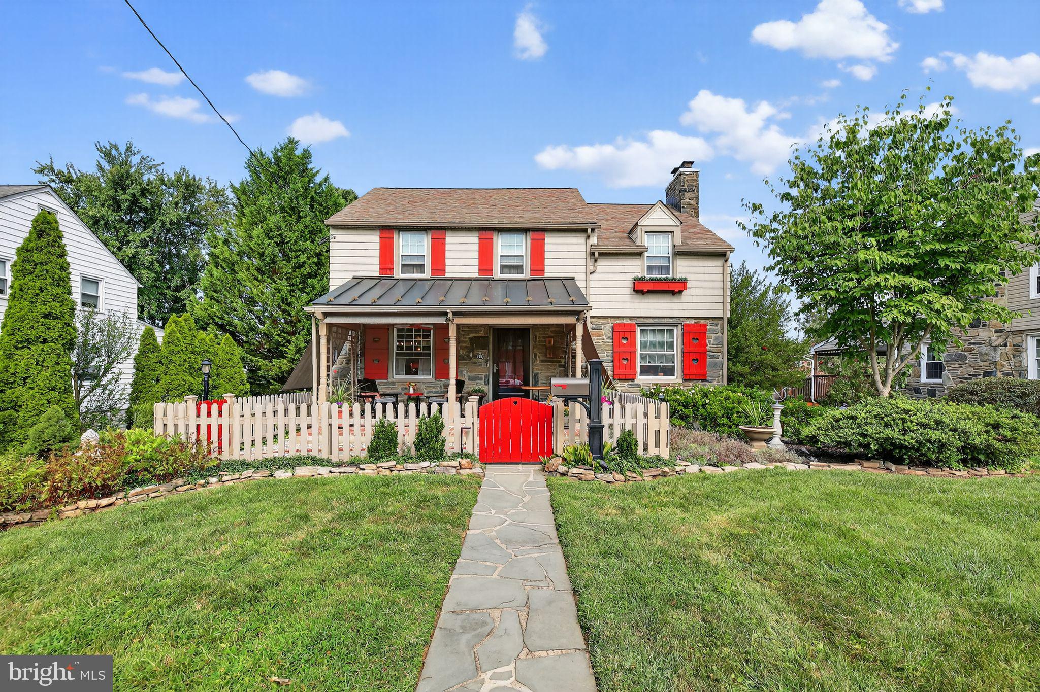 Welcome to this picture-perfect stone colonial, brimming with character inside and out, ideally located in the Dream Valley neighborhood in the heart of Springfield. A picket fence and bold red shutters frame the inviting covered front porch—an ideal spot to sip a glass of wine, read a book, or simply enjoy crisp fall evenings and warm spring afternoons. Step inside to find gorgeous hardwood floors and a sun-filled living room enhanced with wainscoting, crown molding, and a cozy gas fireplace. The show-stopping four-season room offers stunning hardwood floors offset by warm-toned walls, bead board accents with chair rail, and a gas fireplace that make this space truly pop. Walls of windows flood the room with natural light and provide seamless access to the backyard oasis. The heart of the home is the country-style kitchen, blending rustic charm with modern updates. It features a butcher-block center island with pendant lighting, granite counters, stainless steel appliances, stainless farmhouse sink, beadboard and chair rail, and a lovely tile backsplash. The kitchen opens to the dining area, highlighted by a charming built-in bench that makes the perfect breakfast nook or casual gathering spot. The first floor also offers an updated half bathroom for added convenience. Upstairs, the primary suite provides generous closet space, access to the walk-up attic, and a faux fireplace with mantle and gorgeous tile surround that adds a touch of charm and warmth. Three additional spacious bedrooms with plenty of closet space and an updated hall bathroom with beautiful trim outlining the bead board wall and an upgraded vanity complete the second floor. The finished lower level includes a comfortable lounge area—perfect for movie nights or watching the big game—plus a separate utility room, oversized laundry area with large sink, and access to the half garage for storage or hobby space. Outdoors, enjoy a private backyard retreat with a spacious storage shed and an oversized driveway that accommodates 5+ cars. Additional highlights include gas heat, central air, and classic stone construction. This property offers so much charm and has been kept in perfect condition—the owners’ pride of ownership truly shines.