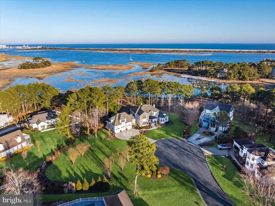 9515 Harbor Lights Dr. is more than a home—it is a lifestyle, a legacy, and an aspiration brought to life. Positioned in one of the most desirable waterfront settings in West Ocean City, this masterfully designed, custom-built waterfront residence sits on over 1.39 acres at the end of a private cul-de-sac, delivering estate-level privacy and an elevated coastal lifestyle within the Ocean Reef community. The setting offers panoramic views of the bay, the unspoiled natural beauty of Assateague Island—renowned for its protected shoreline, wild horses, and untouched coastal landscape—the Ocean City Inlet, and the iconic skyline of the world-famous Boardwalk, complete with the Ferris wheel and roller coaster. From the moment you step inside, the intention of design is immediately felt. A custom front door featuring circular glass detailing sets the tone, with this signature motif thoughtfully repeated in complementary architectural elements throughout the home. An elegant foyer with designer lighting opens to a dramatic great room, where walls of glass flood the space with natural light and frame sweeping water views. The kitchen is a true chef’s playground, anchored by an oversized island, professional-grade appliances, custom cabinetry, and bayfront dining—designed for both elevated entertaining and everyday enjoyment. The open-concept layout ensures seamless flow between living, dining, and entertaining spaces, all oriented to maximize the home’s breathtaking waterfront setting. This custom coastal residence offers 5 bedrooms, 3 full bathrooms, and 1 guest bathroom, along with a den/office/media room that could even function as a 6th bedroom, thoughtfully designed to balance luxury and livability. The owner’s suite is a private sanctuary, generously scaled and appointed with a sitting area, wet bar, and gas fireplace set into a striking statement wall. A private balcony captures expansive bay views, while the spa-level bath and walk-in closets complete the retreat-like experience. A separate staircase leads to a beautifully appointed guest suite, a design choice focused on maximizing privacy, autonomy, and comfort—ideal for long-term guests, in-laws, or live-in staff. This suite features a combined living room and office space, sauna, bayfront bedroom, and en suite accommodations, offering a true secondary residence within the home. Outdoor living is elevated to a resort-caliber experience, with multiple levels of maintenance-free Trex decking creating distinct dining and lounge areas, complemented by a built-in grill and bar island with flexible seating, fire pit lounge, and tranquil fountain—perfect for entertaining against the backdrop of the bay. Completing the property is a collector’s three-car garage with finished flooring and a built-in workstation, offering both functionality and refinement. Every element of this home reflects intentional design, curated craftsmanship, and a commitment to coastal luxury living at its highest level.