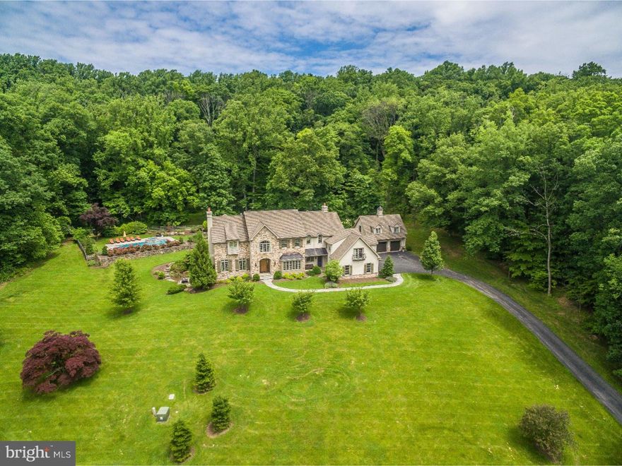 This luxurious custom home is majestically situated on 22 acres of land in Upper Makefield. A long winding driveway with trees opens up to a gorgeous estate positioned perfectly to enjoy long distance views. Once inside one will see beautiful hardwood floors, rich colors and upscale decor. The formal Dining Room has a large marble built-in, great for storing all your dining needs, and custom Butler's pantry for entertaining. The Formal Living Room, lined with custom millwork and a gas fireplace making it a wonderful spot to curl up on a cold night. The Designer Kitchen is the heart of the home with an over-sized granite island with seating for 5. Stainless steel appliances, tile backsplash and built-in fridge with cabinets and drawers finish off the lavish Kitchen. A Morning Room is open to the kitchen and Gathering Room featuring a massive 4 panel window and glass doors to the stone patio. The Gathering Room features a live-edge wood mantle engulfing a wood fireplace and plenty of overhead lighting. There are two half baths and a large Mud Room with a dog shower completing the first level. The Main Suite has a luxe sitting area with built-in storage cabinets, two walk-in closets, a gas fire place and a custom marble/mosaic flooring leading into the Master Bath. Spacious secondary bedrooms, homework nook and upstairs Living Area complete the 2nd level. The finished Lower Level is equally impressive with the rest of the home with a gym, a built-in kitchenette, wine cellar, gas fireplace and a full bath. There is a 3-car attached garage and a detached 2 car garage with a possible au pair suite above, finished Flex space. The backyard landscape features a stone flagstone patio with a wood fireplace and inground pool. This professionally landscaped and decorated home brings a sophisticated, upscale vibe to historic Bucks County.