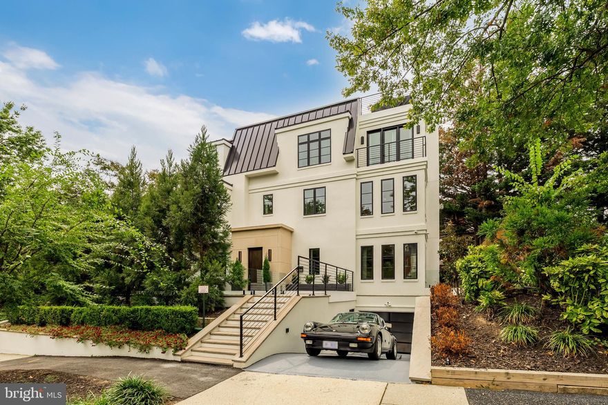 Defined by a striking white stucco façade, sculptural limestone archway, and oversized symmetrical Marvin windows, this Silverstone Group residence presents a distinctive contemporary presence in the coveted Cleveland Park neighborhood.

Spanning approximately 5,020 square feet, the home offers five bedrooms, five full bathrooms, and one powder room, thoughtfully designed for both elegant entertaining and comfortable everyday living.

The residence features eight outdoor living spaces, including a rooftop terrace with hot tub, outdoor kitchen, integrated sound system, and fireplace, creating an exceptional setting for entertaining above the city.

At the heart of the home, the chef’s kitchen pairs sculptural design with functionality. Porcelanosa cabinetry and Carrara marble surfaces frame an oversized island with integrated dining, complemented by a full suite of seamlessly integrated Miele appliances.

Adjacent to the kitchen, a fully appointed butler’s pantry with its own beverage refrigerator, dishwasher, and sink connects to a covered outdoor entertaining terrace through a convenient service window. The terrace is designed for year round enjoyment with built in heaters and a wood fired pizza oven, and extends beneath a pergola with adjustable louvers that allow the space to transition between open air dining and shaded outdoor living.

The primary suite occupies a tranquil corner of the home with three exposures, a fireplace, automated Hunter Douglas window treatments, a spacious walk in closet, and a light filled five fixture marble bathroom.

Additional bedrooms offer en suite baths and generous storage, with a convenient second floor laundry room.

The fully finished lower level includes a media room, gym, artist’s studio, temperature controlled wine cellar, guest bedroom with en suite bath, full laundry room, and a private one bedroom au pair suite with its own exterior entrance.

French white oak flooring, custom millwork, and layered lighting create warmth throughout the residence. Modern comforts include a multi zone Sonos sound system, multi zone climate control, a climate controlled garage, an exterior storage room adjacent to the garage, and mature landscaping that enhances privacy.

A rare offering that combines contemporary architecture, refined materials, and expansive indoor outdoor living in one of Washington’s most sought after residential enclaves.