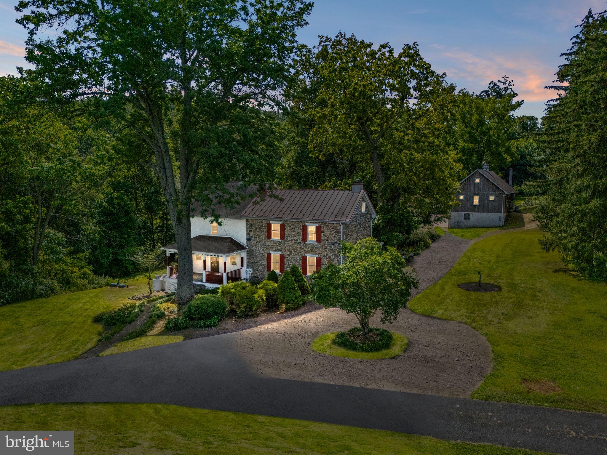 This home could be featured in Country Living Magazine. Here is your opportunity to own a 225-year-old stone farmhouse, originally built in the 1800s and and has been meticulously renovated since 1997. The residence blends authentic colonial charm and history with the comfort of modern amenities.
Step onto the covered front porch and through the doorway into a living room full of character, highlighted by exposed beams and a walk-in stone fireplace with a wood stove insert. The wainscoted dining area is the perfect gathering space, adjoining an open-plan kitchen that features an island, generous prep areas, and ample cabinetry. Just off the kitchen you’ll find a sun-filled mudroom, full bath, and a well-appointed laundry room with sink, worktop, and storage.
Upstairs, the second floor offers three bedrooms (one of which is a loft-style bedroom overlooking the living room) and a full bath, where the exposed stone walls of the original structure add unmatched atmosphere.
The grounds are equally impressive. A two-story barn includes an impressive upstairs workshop, while the lower level features horse stalls. A charming cottage/guest house, currently used as an office, adds flexibility to the property. Additional outbuildings, a fenced pasture with run-in shed, gardens, and a brick patio complete this bucolic setting.
Come explore the property and imagine the lifestyle and possibilities that await you.