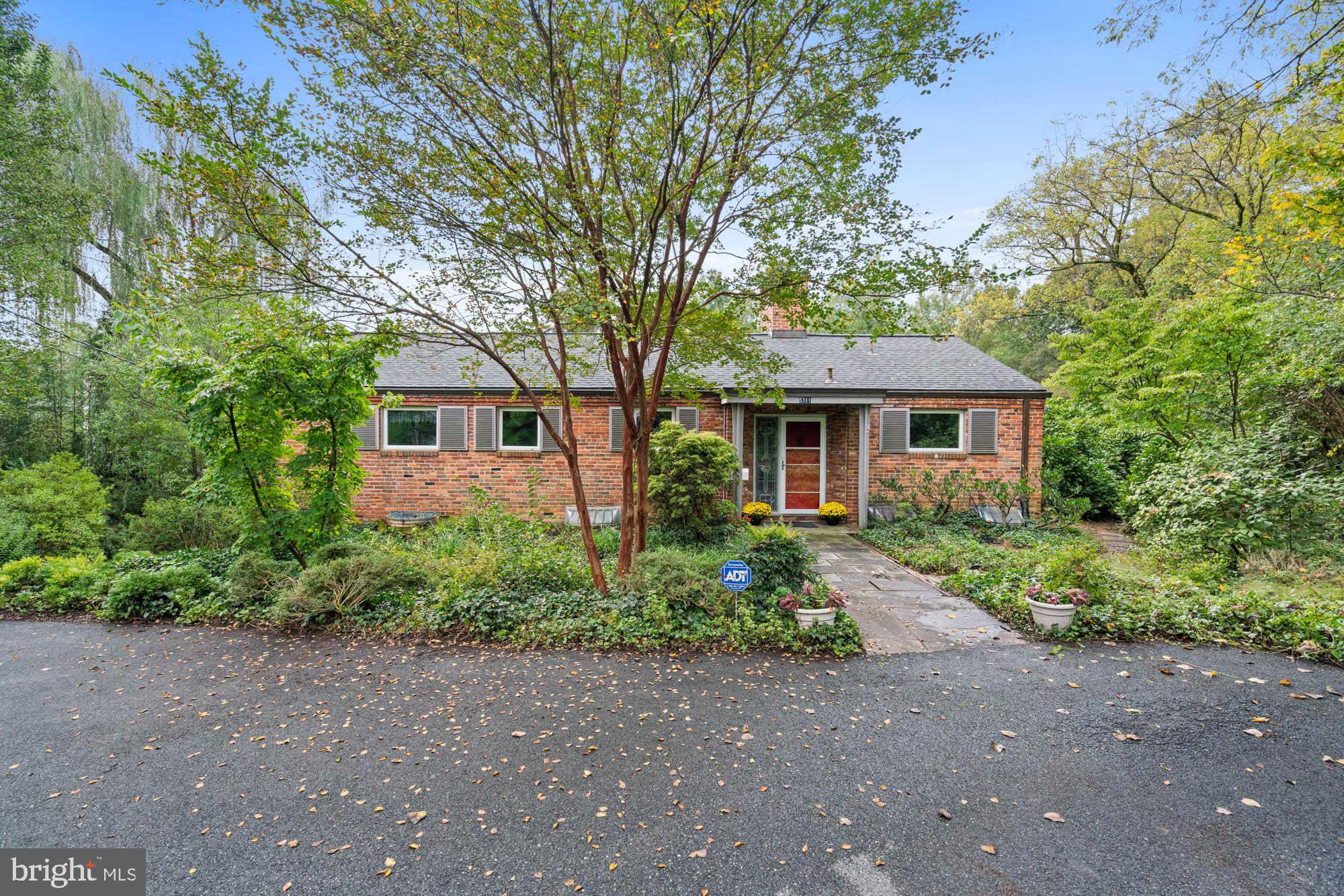 Serenely nestled on nearly an acre in the heart of the Green Acres neighborhood of Bethesda, this distinctive mid-century modern home delivers the most unique suburban setting with great convenience to Washington, DC, downtown Bethesda, and Northern Virginia.
There is a wonderful sense of privacy in nature with expansive mature tree top views and rolling, verdant grounds. Stone walkways and a back terrace spanning the length of the home take advantage of the natural views - perfect for outdoor gatherings and relaxation. This tranquil brick and slate home encompasses approximately 2,900 +/- square feet on two levels of living and enjoys four bedrooms and three full bathrooms. Featuring one-of-a-kind details throughout, including stone and exposed brick walls, gleaming hardwood and hand-laid stone floors, two fireplaces, and light-filled rooms with oversized windows. Additional offerings include an attached workshop, potting greenhouse, a storage shed, and a spacious driveway for ample off-street parking.
The nearly acre lot is resplendent with mature trees, flowering bushes, and a variety of plantings that bloom throughout the year. The rolling topography undulates from the stone terrace as it cascades down towards the creek bed. Backing to protected wooded parkland, the lot offers ample space for gardening, romping with dogs or children, and a quiet, verdant respite from the busy life that surrounds the property. Subdivided decades ago, this parcel was designed to provide a true oasis in the middle of a close-knit typical suburban development.
5311 Allandale Road benefits from urban-suburban living at its finest. The Little Falls Swimming Club, the Capital Crescent Trail and neighborhood parks close-by, while being convenient to the Friendship Heights Metro, many shops, restaurants, bus stops, major transportation routes, with easy access to DC, World Bank, IMF, Embassy Row, NIH, Walter Reed and other major employment centers. A wonderful opportunity to make this peaceful retreat your own! Westbrook, Westland, and B-CC schools serve the neighborhood.