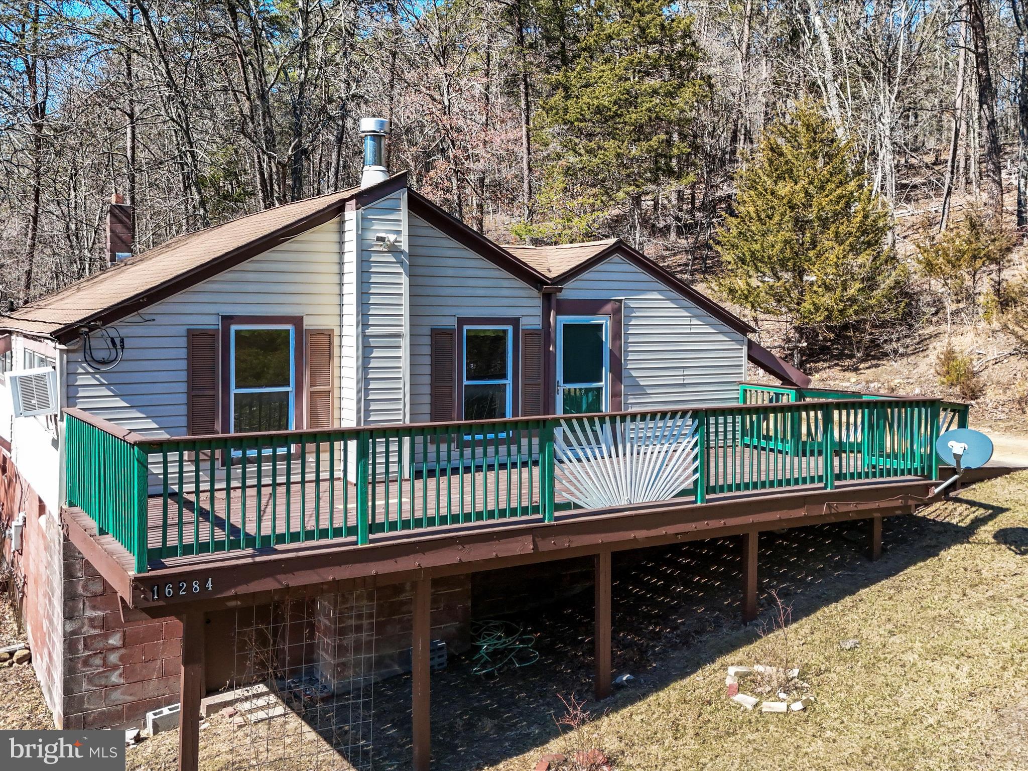 This charming mountain cabin, secluded among the trees near the Cacapon River is perfect for a weekend retreat or full-time living. Set on 2 private acres, this inviting getaway features nearly 1,000 sq. ft. of living space with 3 bedrooms and 1 bath. The cozy living room has a wood stove and is bathed in sunlight that streams through large windows, while cathedral ceilings with exposed wood beams add to its rustic character. The spacious eat-in kitchen is ideal for gathering. Outside, a welcoming front porch and a large, private back deck provide the perfect spots for grilling, entertaining, or unwinding by a fire pit. The property also boasts an established perennial flower garden, a fenced vegetable garden, and a tool shed. While not directly on the water, the home includes deeded access to the Cacapon River, offering easy opportunities for outdoor recreation. With low property taxes and a peaceful, nature-filled setting, this mountain escape is a place where every day feels like a vacation. And with spring just around the corner, now is the perfect time to secure your own retreat and watch the landscape come to life with blooming flowers, fresh greenery, and endless outdoor adventures. Motivated seller- schedule your showing today!!