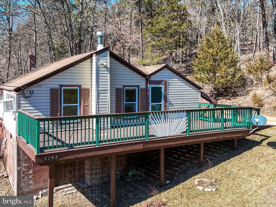 This charming mountain cabin, secluded among the trees near the Cacapon River is perfect for a weekend retreat or full-time living. Set on 2 private acres, this inviting getaway features nearly 1,000 sq. ft. of living space with 3 bedrooms and 1 bath. The cozy living room has a wood stove and is bathed in sunlight that streams through large windows, while cathedral ceilings with exposed wood beams add to its rustic character. The spacious eat-in kitchen is ideal for gathering. Outside, a welcoming front porch and a large, private back deck provide the perfect spots for grilling, entertaining, or unwinding by a fire pit. The property also boasts an established perennial flower garden, a fenced vegetable garden, and a tool shed. While not directly on the water, the home includes deeded access to the Cacapon River, offering easy opportunities for outdoor recreation.  With low property taxes and a peaceful, nature-filled setting, this mountain escape is a place where every day feels like a vacation. And with spring just around the corner, now is the perfect time to secure your own retreat and watch the landscape come to life with blooming flowers, fresh greenery, and endless outdoor adventures. Motivated seller- schedule your showing today!!
