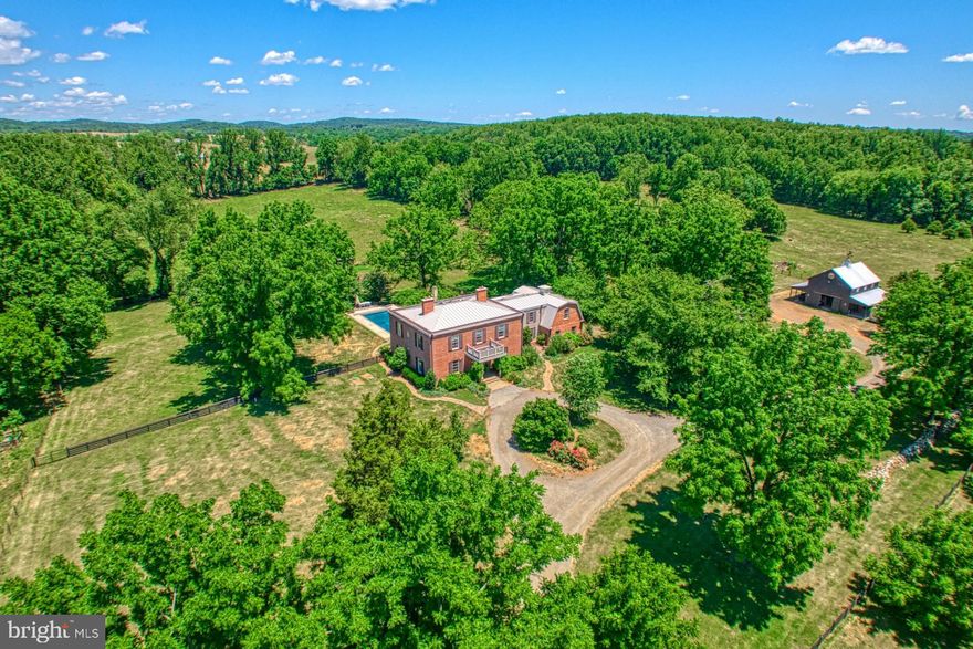 PLEASE DO NOT DISTURB THE OWNER.  DO NOT DRIVE ONTO THE PROPERTY WITHOUT AN APPOINTMENT. Please arrange for a private showing with  Listing Agents.  Seller is requesting a 4 hour notice for appointments. Buyer is responsible for roll back taxes should the property be removed from  current land use.
This magnificent respite encompasses the unrivaled reconstruction of the original 1839 true 4-square Brick Colonial home providing over 5000 square feet of refined living space. Re-imagined and rebuilt in keeping with historical integrity, the owner re-purposed original elements like barn wood beams, bricks and stone to integrate history with modern amenities and thus bring you this 6 bedroom, 6 bathroom extraordinary residence offering a truly enchanting lifestyle.
Open the front door to an enormous foyer flanked by a living room and formal dining room with French doors opening to a side patio. The gourmet kitchen has Vermont Darby marble on the oversize center island with a built-in Steam over by Miele, a Blue Star range with two of their infamous 22,000BTU burners, 2 Samsung stainless steel refrigerators, custom cabinetry, an antique kitchen sink that overlooks the pool and a huge pantry. A rear staircase and hall was created that leads to a "tucked-away" main level bedroom and full bath. Original to the house is a cozy study with walls of built-in shelving and a gas fireplace.
The upper level offers 3 spacious secondary bedrooms, a "Jack and Jill" bath and a hall bath. The primary suite with its primary bath (soaking tub and walk-in shower) and large walk-in closet connects to an oversize sitting room/office/nursery.  And that is  not all...the current owner added a 5th bedroom, full bath and a large family room with fireplace> All this is quite separate from the original bedroom room floor plan. 
The grounds now boast a  luxurious  heated pool with a Wisteria covered cabana with fireplace and surround sound. Among the out-buildings, is a fully outfitted 2-story barn/certified commercial kitchen, a foaling barn, an equipment storage barn and various run in sheds.  With fields of livestock, paddocks for horses, chicken coops of eggs, overall, life on this  farm is a blend of hard work, community, and connection to nature, with the luxury of amenities like an in-ground pool and a remarkable home to enhance the experience.
Come see this storybook escape...a piece of the good life at Junco Hill Farm.