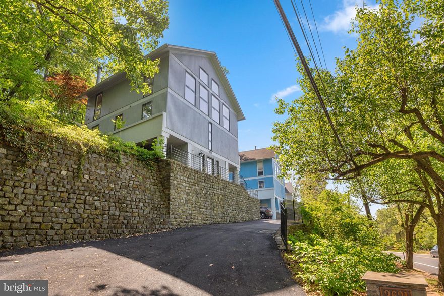 Perched among the treetops in sought-after Arlington Ridge, this dramatic, light-filled modern home seamlessly blends luxury, comfort, and convenience. Ascend the staircase and be immediately rewarded with breathtaking, treetop views that transform the upper level into a peaceful sanctuary.  Soaring 15-foot ceilings and expansive atrium windows flood the open floor plan with abundant natural light, creating a warm, airy atmosphere ideal for both elegant entertaining and relaxed family living. With the views as the focal point, the living area also features a cozy fireplace and flows effortlessly into a beautiful gourmet kitchen, complete with premium finishes and ample counter space for gathering. Step outside to your private backyard oasis, where terraced landscaping, a serene pond, two stone patios, and lush perennial gardens provide a tranquil escape. The spacious primary suite offers a luxurious retreat, boasting a spa-like bathroom with a separate separate tub and shower. The second and third bedrooms, thoughtfully positioned on either side of a shared full bathroom, offer flexibility—one of which could easily serve as a comfortable home office with built-ins at the ready.  Recent updates to note: New roof & gutters with gutter guards (2019); hardwood floors added to bedrooms (2022); new hot water heater & filter (2025); resurfaced driveway (2025); new bathroom fans (2025). With three-car parking, generous storage, and close proximity to the Pentagon, DC, Reagan National Airport, I-395, shops, restaurants, parks, and public transit, this home delivers the perfect balance of privacy, sophistication, and accessibility. Truly a unique offering that you need to see to experience the incredible setting!