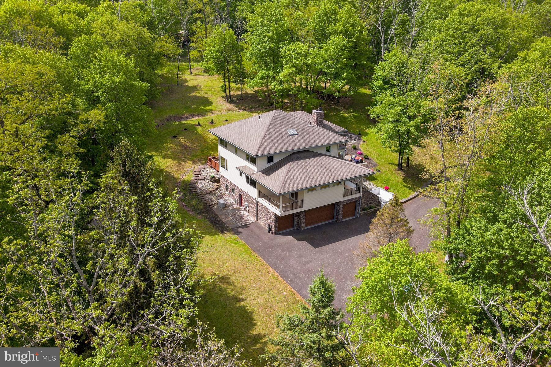 Built with a significant emphasis on quality and sustainability, the European-influenced "San Souci" is offered for the first time. Convenient to Newtown, Yardley and New Hope, this home is a world away from typical newer construction, this privately situated, custom residence is on 5.9 acres high above the historic Delaware River canal, perfectly located for walking and bicycling as well as for easy access to Princeton, Philadelphia, and train service to New York and beyond. Step inside this LEED-certified home and feel how open and light-filled the entire main living level is. Custom Andersen windows and doors galore frame views and let the sunshine in on timeless marble floors. A Canadian-built soapstone wood-burning fireplace can warm the living space for hours, supplemented by the home's efficient geothermal and solar systems with hot-water radiant tubing in place beneath most of the home's floors. The open plan is flexible and smartly designed with spaces for dining, including a charming hidden breakfast nook, seating areas, a private home office, a four-season sunroom with fireplace and a stunning kitchen. Designed for the serious cook, the kitchen has storage galore with a walk-in pantry closet and custom Amish-made cabinetry, professional-grade Thermador appliances (two full-size wall ovens, warming drawer, 48" gas cooktop with powerful ventilation hood, refrigerator/freezer, dishwasher), wine chiller, built-in microwave/convection and a large island topped in a single sheet of granite, all lined in fun LED rope lighting. Whether for daily needs or special occasions, this kitchen will perform quite capably, and the cook will appreciate the views. This home has a remarkable amount of indoor-outdoor flow, including access to a deck with built-in seating and BBQ space just off the kitchen, a large corner veranda off the dining area and a patio with built-in firepit and seating off the sunroom. And that is just the first floor. The open central stairwell, where there is plenty of gallery-style wall space for art and a skylight, leads to private quarters on the second floor. An owner's suite with a large private balcony and ample space for a seating area includes a large bath with extra-deep steeping tub, oversized two-person shower and two wall-hung vanities plus three closets, including walk-in with built-ins. A second en suite bedroom with private balcony, bedroom with access to a hall bath, and fourth bedroom with a fun "a-ha" entrance and its own full bath complete the upstairs. All bedrooms have hardwood floors and plenty of windows for natural light. A full laundry room with laundry chute is on the first floor and includes generous storage. The finished lower level provides a home theater with built-in sound system and tiered seating, a full gym, full bath and space ready to become your wine cellar. Utility rooms and a four-car garage complete this level. To support the LEED living environment, this home has a Honeywell air filtration system, cistern for collecting rainwater for gardening/car washing, well water treatment system, whole-house vac, plus the security and comfort provided by a whole-house generator. "San Souci" is an ideal residence for the buyer seeking a thoughtfully designed house offering privacy, home office and recreation spaces, and an ideal location just a few minutes from I-95.