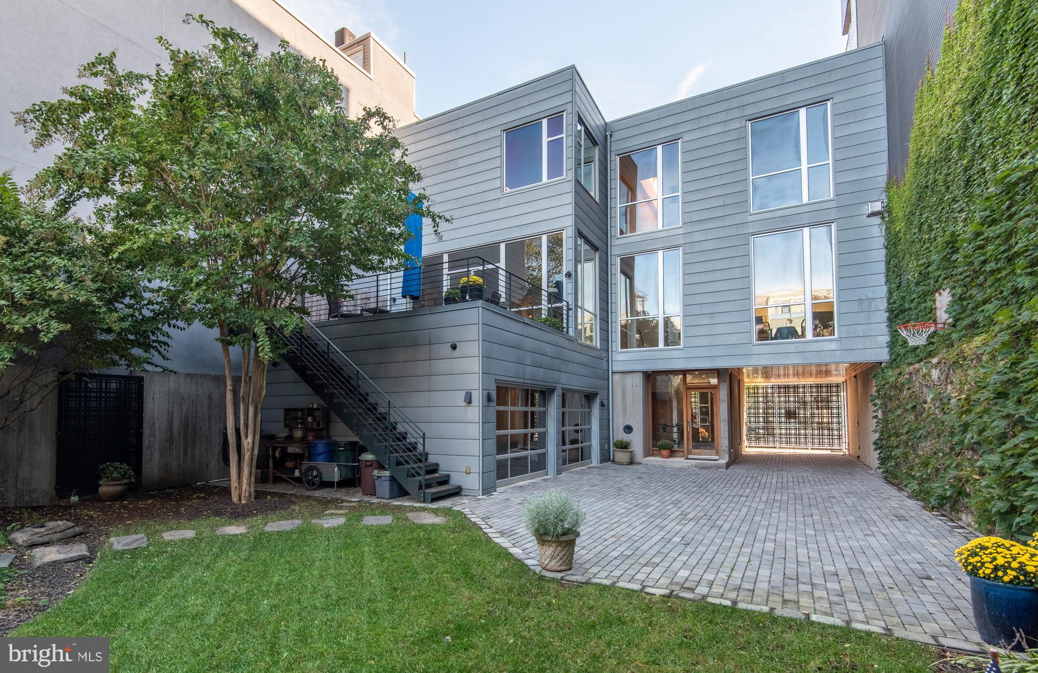 This custom townhouse is unique - designed by AOS Architects for a 45x100 lot with a contemporary exterior and an expansive 4400+ sf of living space. Its private garden, courtyard parking, plus two-car attached garage are unheard of in the city. The rear yard is a landscaped quiet space with mature plantings and the security and privacy of an 8ft concrete fence with gated alley access to nearby Liberty Lands park. The ground floor natural slate entry area includes a coat closet, garage access, powder room, and laundry room. Take the elevator or front stairs up to a magnificent living space with 10ft ceilings, floor-to-ceiling windows with power shades, two separate seating areas, custom gas fireplace, and wall of custom shelves. A stately, oversized dining room and kitchen plus powder room and balcony occupy the other half of this floor. The Kitchen and dining room feature cherry cabinetry by Pappajohn with high-end appliances - SubZero fridge, Wolf stove and microwave, Dacor warming drawer, and two Miele dishwashers - along with eat-in space that faces onto a spacious 16'x20' IPE mahogany deck with stairs to the backyard. The dining room includes cabinetry at either end with a wet bar, under-cabinet fridge, and wine rack. There are three bedrooms and two bathrooms on the third floor with 9ft ceilings. The master bedroom has a separate sitting room with custom built-in desk, gas fireplace and another balcony. All three bedrooms have generous closets with built-ins. The bathrooms are large with designer glass tile, Duravit fixtures, and Hansgrohe faucets. Special features include a central vacuum, intercom system, security cameras, fire sprinkler protection, lawn irrigation system, a basement with an 8ft ceiling, and an office rental space on the ground level providing passive income. The thriving social scene of Northern Liberties surrounds this remarkable home with walkable dining in some of the best Philadelphia restaurants. Cafes, coffee, and neighborhood bars are nearby. Easy access to Center City, the Philadelphia airport, and the sports stadium area. This is a home built for its Philadelphia setting - and for its owners to embrace the Northern Liberties life.