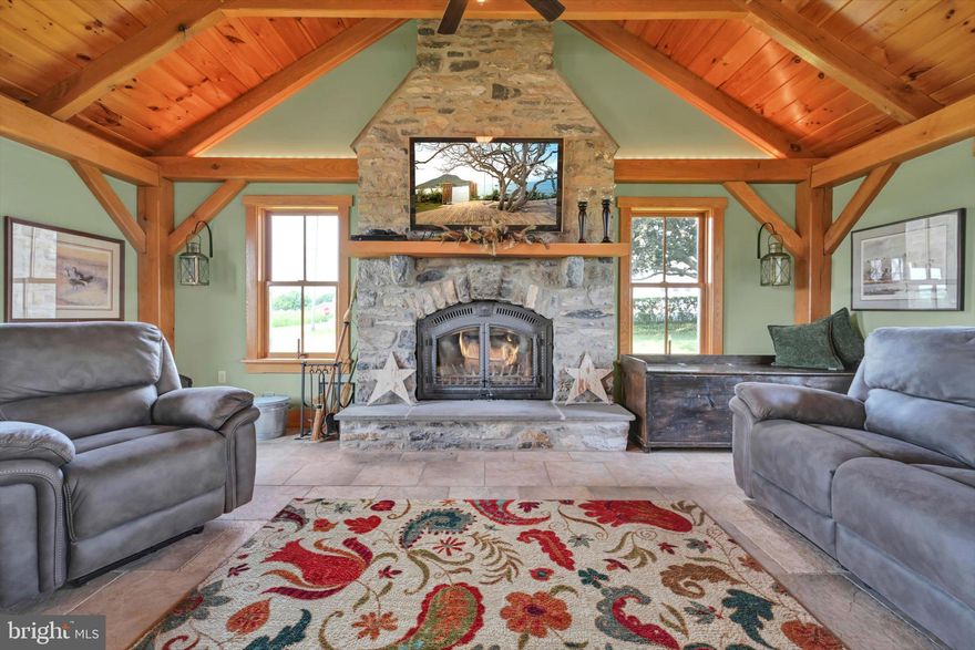 Step into timeless elegance at this masterfully restored 1830 Pennsylvania Dutch Farmhouse
nestled on 13 pristine acres. This 6-bedroom, 3.5-bath historic estate has very recently been fully
renovated down to the studs using reclaimed materials from the original property and local stone
— blending heritage with luxury country living.
The entry of the home not only welcomes guests — it tells a story of tradition, refinement, and
enduring charm. Thru the solid wood doors, tile flooring underfoot, detailed millwork, and high
ceilings offer a blend of timeless craftsmanship and understated elegance. To your left, a hall that
leads to a half bath , lunch nook and entryway to the backyard oasis. Lined with built-in custom
cabinetry, a commercial size refrigerator and full laundry creates the amazing butlers pantry.
The chef's kitchen is the centerpiece, showcasing custom cherry cabinetry, soapstone
countertops, a Viking 6-burner gas range, and a one-of-a-kind wood-fired oven that is often used
for the most fabulous home cooked meals.
Anchored by warm hardwood floors and framed with deep-sill windows, the expansive dining
room is designed to be both inviting and functional. Perfectly positioned between the kitchen and
living areas, it features an open-concept layout that encourages effortless flow — ideal for
everyday family meals or entertaining guests. Natural light fills the space, while the windows
offer scenic views of the pool and horse pastures, creating a picturesque backdrop to every
meal.
Bathed in natural light and warmed by rich hardwood floors, the formal living room on the main
floor is a cozy yet elegant retreat. Oversized windows frame postcard-perfect views of the
surrounding hay fields. At the center of the room, a gas fireplace with brick surround adds
warmth and charm, complemented by handcrafted wood beam supports that honor the home’s
historic architecture.
When your guests get a little too cozy, a thoughtfully designed main-floor guest or in-law suite
offers a private bedroom and full bathroom, ideal for multi-generational living.
At the heart of the home lies the breathtaking Great Room , a true showcase of traditional
Germanic peg-built craftsmanship. Soaring vaulted ceilings and exposed wood beams create
an open, cathedral-like atmosphere, while the rich knotty pine finishes bring warmth and rustic
elegance. A striking floor-to-ceiling stone fireplace with a wood burning stove not only
anchors the space with historic character, but also provides radiant heat that rises to warm the
second floor. Bathed in natural light from all sides, this room is both a gathering space and a
sanctuary — ideal for cozy evenings by the fire or entertaining under the glow of its timberframed beauty. The charming home office featuring custom cabinetry and desk crafted from
trees on the property, set against authentic stone walls and wood beams.
The second floor features a spacious primary suite with a walk-in closet and a luxurious en-suite
bath, complete with a full-body Jacuzzi shower. Two additional bedrooms each offer generous
closets and picturesque views of the surrounding pastures from every deep-set window. A full
bath with double vanity and tub/shower combo, along with a discreetly tucked-away laundry
area, completes this level.
Surprisingly, the third floor opens up to two oversized bonus rooms—ideal for bedrooms, hobby
spaces, or guest quarters—each room showcases original wood overhead beams and gleaming
hardwood floors.
Step out onto the expansive back deck and take in panoramic views of the heated pool, charming
pool house, and sweeping horse pastures beyond. A lighted stone staircase gracefully descends
from the deck to the pool area, creating an inviting and elegant transition for both daytime
enjoyment and evening entertaining.
REMARKS CONTINUED BELOW :