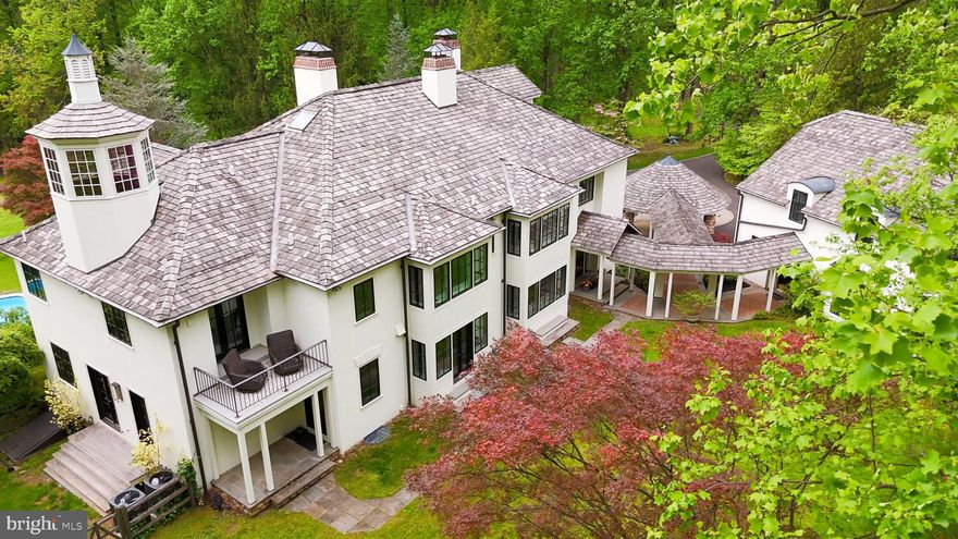 Transported into a World of Utmost Sophistication and Privacy-
Prepare to be seduced by one of the finest estate homes in Solebury, "Birdsong", where understated grandeur meets impeccable craftsmanship. This exceptional residence—a masterful renovation by acclaimed interior designer Timothy Summers Bailey—has been transformed into a sanctuary of refinement and serenity.  Swathed in creamy off-white tones, the interiors provide a tranquil, neutral canvas for showcasing treasured furnishings and art.
Sophisticated Finishes & Thoughtful Craftsmanship Throughout-
Every inch of this estate reflects a dedication to timeless design and elevated materials, blending old-world elegance with modern luxury. Rich ash flooring flows seamlessly throughout, while expansive windows and doors, installed in 2023, bathe the interiors in luminous natural light, amplifying the home’s serene ambiance.
The journey begins in a breathtaking foyer that sets the tone for the home’s dramatic yet inviting interiors. To the left, an intimate parlor with fireplace transitions gracefully into a generous dining room, ideal for elegant entertaining or intimate gatherings. Beyond the foyer, a moody, atmospheric whiskey library with a wood-burning fireplace beckons for fireside conversations and quiet reflection.
At the heart of the home, a soaring great room features a wall of windows framing views of the pool and lush grounds, dissolving the boundaries between indoors and out. This spectacular space flows effortlessly into the chef’s kitchen—a showpiece adorned with Carrara marble, bespoke cabinetry, and a striking Venetian plaster hood. A fully equipped butler’s pantry with a secondary dishwasher ensures effortless entertaining, while a walk-in pantry, chic powder room, mudroom, and media room complete the meticulously designed main level.
Elevated Living Across Every Level-
Upstairs, the private quarters offer a sumptuous primary suite with a spa-like bath wrapped in Carrara marble across the countertops and expansive shower walls, with Carrara mosaic tile underfoot. Custom white oak cabinetry elevates the space to a new level of indulgence.
Two additional en-suite guest rooms, a dedicated office, and a designer-appointed laundry room complete the second level. The third level features an expansive en-suite guest retreat, providing exceptional privacy for extended stays.
The lower level is designed for leisure and recreation, featuring an en-suite guest room, fitness room, secondary kitchen, and additional laundry—perfectly positioned for seamless poolside entertaining—alongside a full bath for added convenience.
Resort-Like Grounds & Amenities-
Extending the estate’s appeal, a charming guest house offers a private one-bedroom retreat with one and a half baths, full kitchen, a cozy fireplace, and an outdoor entertaining area designed for unforgettable evenings under the stars. Completing the property are a three-car garage, a picturesque pond, and a storage shed—all seamlessly integrated into the manicured grounds, delivering the feel of a private resort oasis.
Every space within this estate is illuminated by carefully curated lighting fixtures, enhancing the sophisticated material palette and creating an artful glow that transforms the property after sunset into an enchanting, private world of your own.
This seductive estate offers far too much to capture here, and must be experienced to fully appreciate its rare blend of privacy, craftsmanship, and world-class design.
Low taxes, property in ACT 319