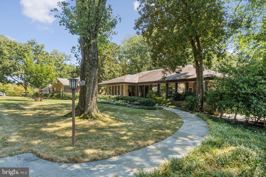 Welcome to this stunning 4-bedroom, 3.5-bathroom Mid-Century Modern residence nestled in the highly sought-after Riverwood neighborhood of North Arlington, 3 miles and one stoplight from Washington, D.C. This architectural gem with expansive windows sits on a vast 1.362-acre lot and offers a unique sanctuary where design and nature converge. 

Designed by John S. Samperton, an apprentice to Frank Lloyd Wright, it stands high above the rock cliffs of the Windy Run waterfall trail, offering a private path to the park and 180-degree forest views. Also nearby is the Custis bike trail.

House Features & Tranquil Outdoors 🌿
The home is a testament to seamless integration with nature.

Lush Backyard & Integration:
The expansive property feels like a secluded retreat. Open your windows to the gentle cascade of your own personal waterfall feeding a large, natural stacked stone pond with waterlilies, extending into gardens and forest. Enjoy outdoor living on the two-level rear bluestone patio, grilling patio, or under the Wisteria-covered pergola. The property adjoins Windy Run Park and extends into the Chesapeake Bay Preservation area, ensuring unrivaled privacy.

Luxury Interior Amenities:

Thoughtful Materials: Features include unique cork flooring, solid walnut cabinetry, cypress wood walls and beautiful oak flooring, consistent with the architect’s vision.

Kitchen & Dining: The gourmet kitchen (updated in 2006) retains its character with an original mid-century stainless steel range hood and a classic George Nelson Ball Clock.

Ambiance & Warmth: Two wood-burning fireplaces with striking stacked stone Prairie Style Masonry walls serve as focal points.

Open Design: Enjoy an open plan with high ceilings and vast window walls.

Integrated Living: The former screened porch was fully renovated in 2006 into an interior sunroom.

Premium Detailing: Includes Pella windows, full attic insulation, and updates to the electrical system, foundation, and drainage (2006).

Architectural Design: A Frank Lloyd Wright Legacy 🖋️
Samperton’s design is deeply inspired by Wright’s Prairie Style, perfectly harmonizing the home with its environment.

Echoing Nature: The design masterfully brings nature inside. Cantilevered piers visually echo the tall trees, while the immense Prairie Style Masonry walls at the center make the structure feel built directly against the cliff face.

Light Control: The sweeping overhang of the eaves and slate roof is ingeniously designed to provide cool shade in summer yet flood the rooms with warm sunshine in winter.

Atmospheric Lighting: Calming cove lighting mimics sun filtering through the forest leaves.

Distinctive Details: The home features signature angles, cantilevered pier columns, and masonry detailing. Original architectural drawings are available to the new owner, connecting them to the home's distinguished lineage.

Garages & Exterior Notes 🚗
An attached oversized two-car garage provides secure parking and storage. There is also a detached one-car garage (sold as-is) and dedicated outdoor parking spaces. The exterior features Prairie Style masonry planter boxes. 
This is a rare opportunity to own a piece of architectural history in a coveted, scenic location.

Pre-offer inspections are welcomed and encouraged. Please see the Documents section for age of system and 2 as-is items.
