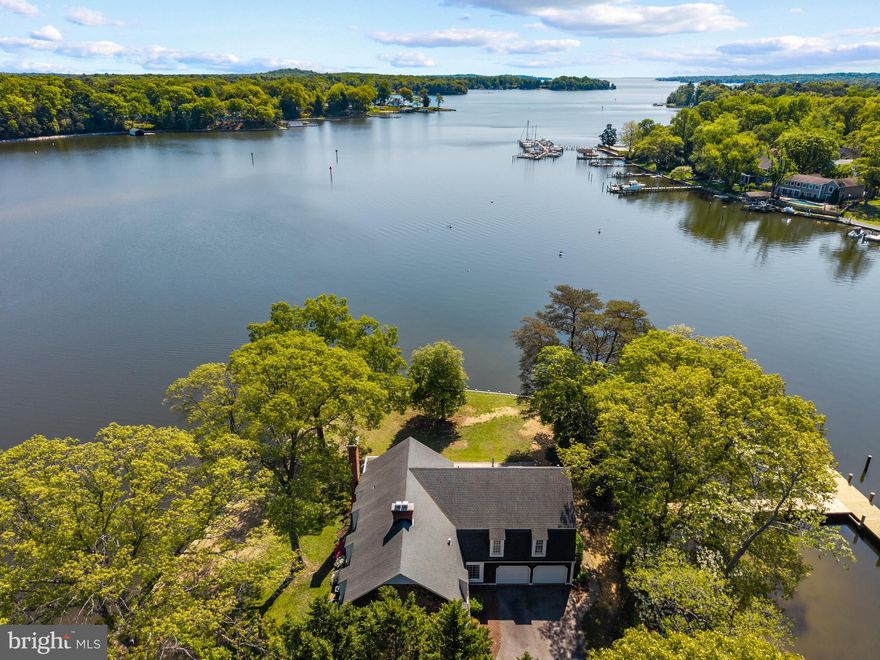 Set on a spectacular point of land along the Magothy River, this rare offering captures panoramic water views in every direction and delivers the kind of waterfront lifestyle that is increasingly hard to find. With an extraordinary 497 linear feet of shoreline, upgraded bulkhead, and a newly constructed pier, the property is wrapped in water, creating a sense of privacy, openness, and connection to the river that defines every moment here.

The new private pier extends into deep, protected waters with the capability to accommodate a large vessel, making this an ideal setting for boating enthusiasts eager to explore the Magothy and beyond to the Chesapeake Bay. Whether it’s early morning departures, sunset cruises, or effortless days spent on the water, this property is designed to fully embrace life on the river.

Inside, the home offers a warm and inviting layout with expansive living spaces that frame the ever-changing waterfront backdrop. The kitchen and adjoining dining area are perfectly positioned to take advantage of the views, while multiple gathering spaces—including a wood-clad great room with fireplace and a sun-filled waterside porch—create a seamless flow for both everyday living and entertaining. Classic detailing, rich wood floors, and timeless finishes provide a strong foundation ready to be enjoyed as-is or elevated to suit your vision.

The upper level features a spacious primary suite highlighted by a private balcony overlooking the water, an ideal retreat for quiet mornings and peaceful evenings. Additional bedrooms offer comfortable accommodations for family and guests, many with their own unique vantage points of the river.

Outdoor living is equally compelling, with a waterside deck, expansive lawn, and mature trees framing the shoreline. The setting invites everything from casual gatherings to large-scale entertaining, all with the Magothy River as your backdrop.

Adding to its exceptional appeal, this remarkable property offers a rare combination of features seldom found in waterfront homes, including the coveted waterfront trifecta of public water, public sewer, and natural gas — an invaluable advantage that provides both everyday convenience and long-term flexibility. Situated just steps from the community pool in the highly sought-after Fair Oaks on the Magothy community and within the Severna Park Blue Ribbon school district, the property seamlessly blends an extraordinary point-of-land setting with an unmatched waterfront lifestyle centered around boating, relaxation, and year-round enjoyment on the water. Welcome Home!