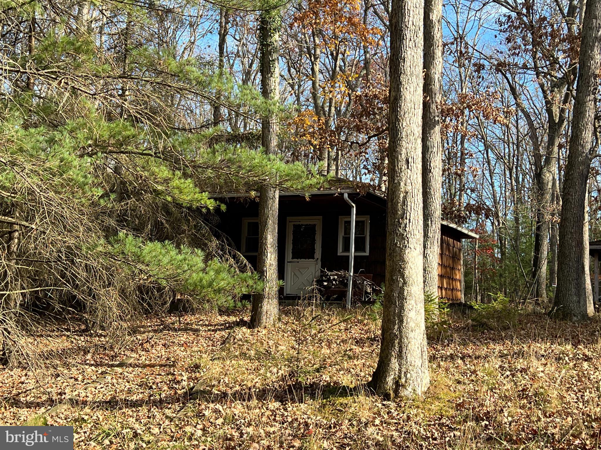 Escape modern life's hustle and bustle and step back to a simpler time with this enchanting two-bedroom, one-bath rustic cabin nestled on a scenic, flat 0.59-acre parcel at Deep Creek Lake, MD. The inviting front porch and charming fireplace create an ambiance of warmth and timeless tranquility, while a large picture window beautifully frames your lush surroundings. An additional separate building expands possibilities for guest accommodations or personal retreats.
Practicality meets pleasure with two extra storage buildings and generous parking space for friends and family gatherings. Boating life is simplified as this property qualifies for a Type A boat permit (pending inspection), allowing two motorized vessels and one kayak. Conveniently located close to Oakland's charming boutiques, dining, and everyday shopping conveniences, as well as Wisp Resort for skiing, golfing, and year-round recreation, this property provides the perfect blend of rustic charm and modern accessibility. Come create lasting memories in your own piece of Deep Creek Lake history! There is a second structure that needs your finishing touches to complete.