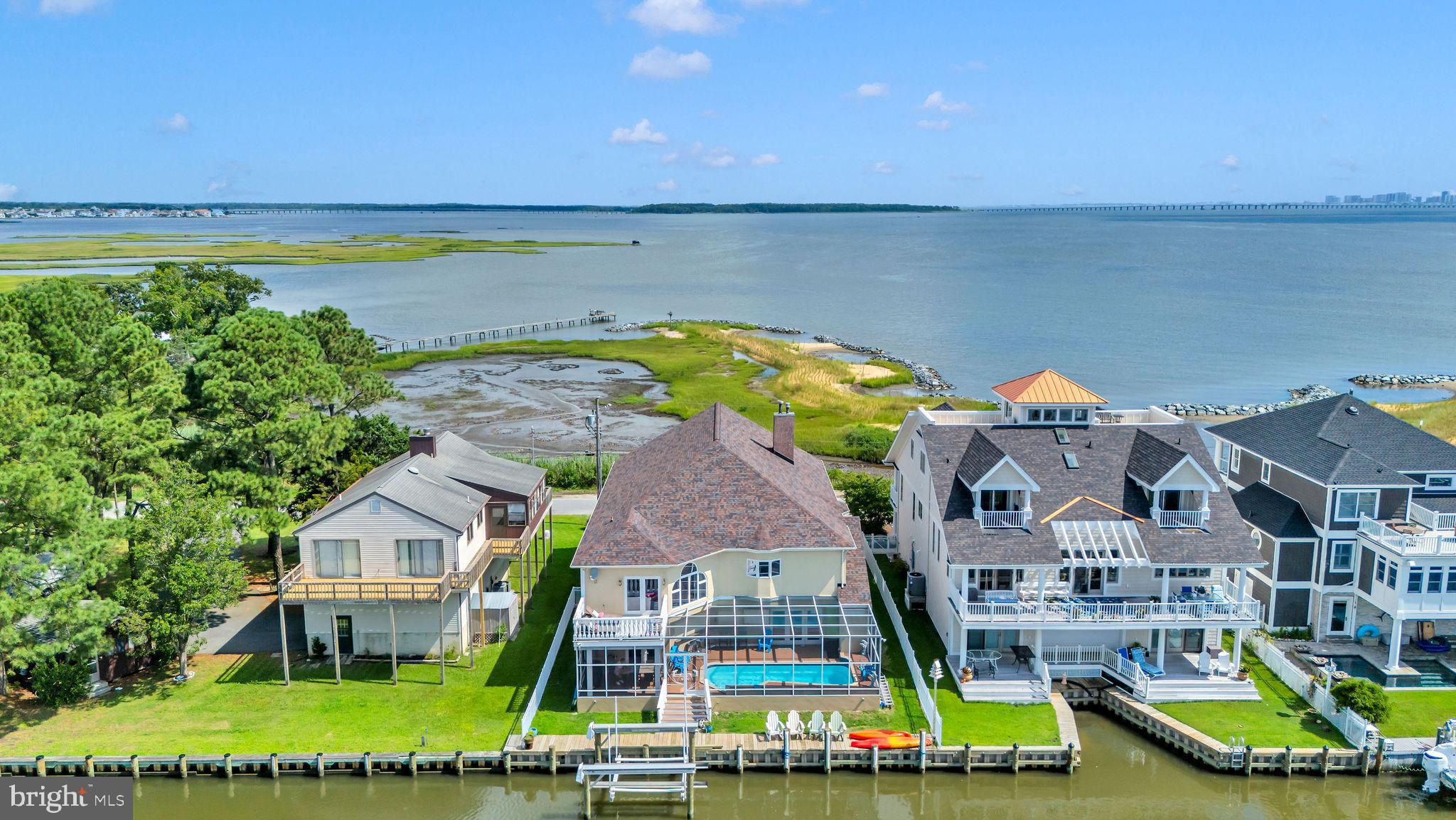 Welcome to the Best of West Ocean City – Where Coastal Elegance Meets Waterfront Luxury
This exceptional south-facing waterfront residence offers panoramic, unobstructed views of the Ocean City skyline, blending refined coastal design with high-end amenities for a truly one-of-a-kind lifestyle. With 60± feet of bulkhead, a brand-new seawall, and a private boat lift just steps from your outdoor living area, this is a water lover’s paradise designed for effortless enjoyment and entertaining.
Step into resort-style living with a fully screened, Florida-style heated pool oasis featuring a tranquil waterfall, outdoor bar/kitchenette, beverage fridge, ice maker, sink and microwave, and bar seating. Whether you’re hosting sunset cocktails or al fresco dinners under the stars, this outdoor retreat brings relaxation and sophistication together beautifully.
Inside, the home offers a thoughtfully designed layout with multiple living zones. The first floor includes a poolside family room with its own washer and dryer, a private guest suite, and two additional serene sleeping retreats—ideal as guest bedrooms, reading nooks, home office, home gym or flex spaces for extended family.
Upstairs, the open-concept living area features a dramatic great room, chef’s kitchen with gas cooktop and premium appliances, and a spacious dining area—perfectly designed for entertaining. The luxurious primary suite is a private sanctuary, offering a electric fireplace, whirlpool spa bath, walk-in closet, and a private balcony overlooking the peaceful canal. Two additional bedrooms, plus the iconic “Whiskey Room” with its cozy fireplace and sweeping bay views, complete the second level.
Additional highlights include an elevator, oversized garage, city sewer, private well with water softener, and recent upgrades including a new roof, updated HVAC system, and an owned propane tank.
From luxury finishes to resort-style outdoor living, this extraordinary property delivers the ultimate in coastal living. Don’t miss your chance to own a true slice of paradise in one of Ocean City’s most coveted waterfront communities.
