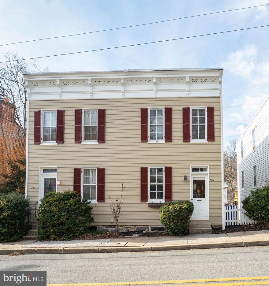 Nestled in the heart of the historic Dickey Mill community in Oella, this three story home offers a rare blend of 1890 millworker charm and thoughtful modern updates. This home stands out for its character, condition, setting, and private parking.

The main level welcomes you with rich hardwood floors and a fully updated kitchen featuring light cabinetry, granite countertops, recessed lighting, and stainless steel appliances. There is ample space for casual dining, while the adjoining dining room offers a clean, open feel, creating a versatile space for everyday meals or special gatherings. A full bathroom on this level adds convenience and functionality.

The second level offers a bright and spacious landing flex space, a beautifully appointed living room with hardwood flooring, and a large office that can easily serve as an additional bedroom. A half bathroom completes this floor.

On the top level, the expansive primary bedroom is accompanied by a third generously sized bedroom and a spacious full bathroom. The bathroom area includes both a walk in closet and a custom reach in closet, providing excellent storage.

Recent improvements include updated bathrooms throughout all three levels, a newly installed stone patio added in summer 2025, exterior wood siding that was repaired and repainted in 2025, and new gutters. Additional features include an unfinished basement for storage, a side deck, a rear patio, and a peaceful wooded backdrop. The property also offers access to a private trail along the Patapsco River, with seasonal river views that enhance the setting and connection to nature.

Dickey Mill was once the largest textile mill in the United States, and today the surrounding community remains one of Ellicott City’s most beloved historic districts. This in demand historic townhouse offers timeless character, modern comfort, and a truly special location within the Oella and Ellicott City area.