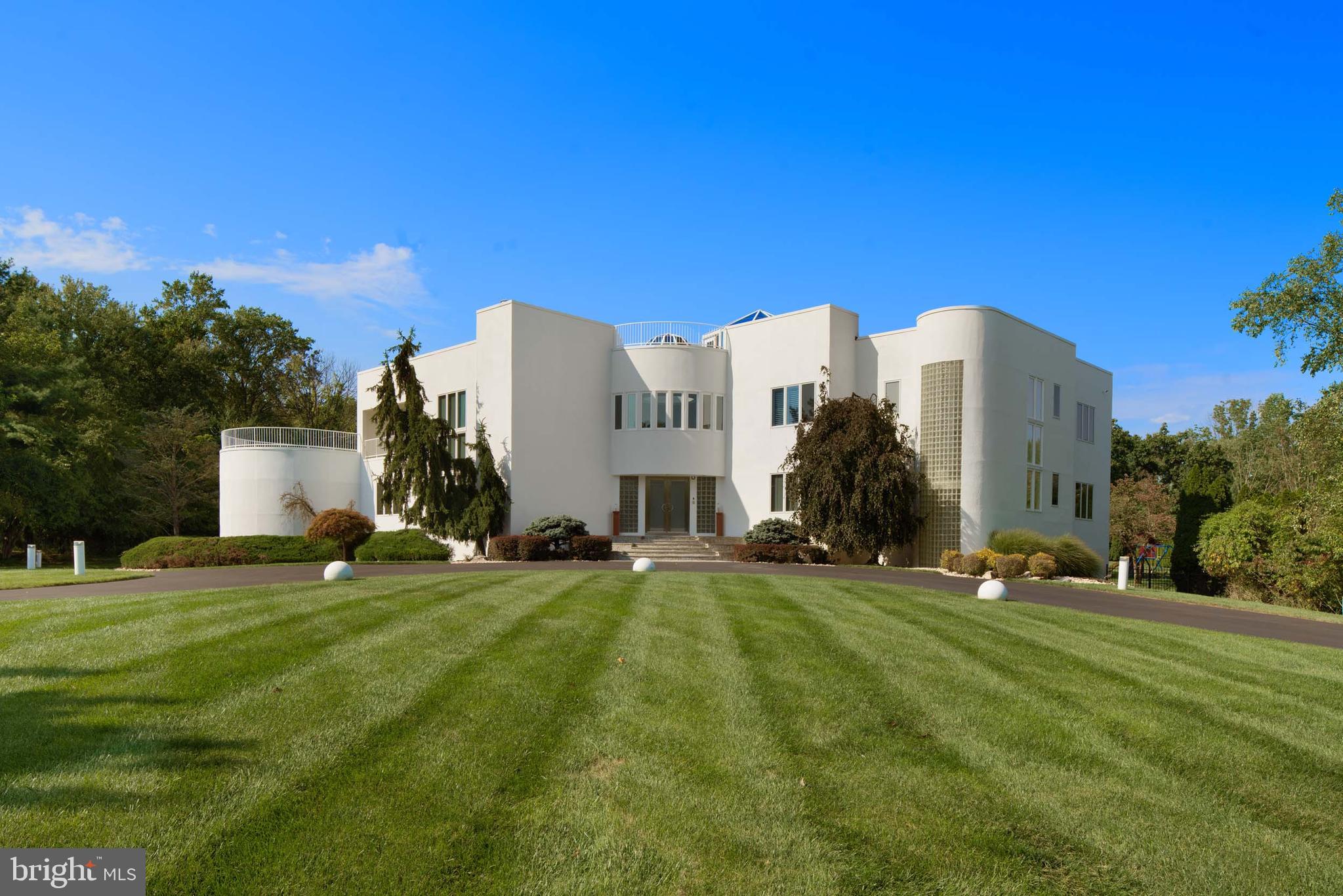 Welcome to 611 Creek Lane, an expansive, light-filled modern residence that blends sleek design with refined luxury. This sun-drenched home is crafted for both entertaining and comfort, with extensive windows and sophisticated details in every space. Enter through a striking two-story foyer, where marble floors and a sweeping double staircase create an unforgettable first impression, illuminated by a domed skylight. To the left, a living room with a conversation pit exudes retro charm, leading to a mirrored dining room that amplifies light and space. At the heart of the home is a cook's kitchen with a unique built-in aquarium at the peninsula, a wet bar, and ample cabinetry and shelving. Outfitted with high-end Thermador and Gaggenau appliances, including a commercial induction range, double ovens, and a steam griddle, this kitchen is made for serious culinary work and relaxed entertaining. Adjacent to the kitchen, a circular breakfast nook opens into the family room with a textured accent wall, fireplace, and access to a sunlit circular sunroom—a serene reading spot to relax while looking over the pool. Completing this level is a first-floor bedroom suite with a walk-in closet and marble ensuite, an office, and a powder room. An additional bedroom suite located off the kitchen can function as an au pair or in-law suite. Upstairs, the primary suite is a private haven, featuring a gas fireplace, wraparound balcony, and wet bar with a beverage fridge. The spa-inspired ensuite includes a sunken Jacuzzi tub by a fireplace, a walk-in shower, and expansive views of the lush backyard. A large walk-in closet with built-ins, a secure safe room, and a dressing area add both style and functionality. An adjoining sitting room with a staircase leads to a one-of-a-kind third-floor atrium with rooftop deck access. Across the hall, a second-floor office with its own balcony creates an inspiring workspace. Three additional bedroom suites each have walk-in closets and private bathrooms, with one suite featuring a private balcony. A secondary staircase leads to the walk out finished basement space with backyard access, ideal for hosting or private relaxation. This level includes a secondary kitchen with bar seating, a private bedroom suite, a full hall bath, and abundant storage. The backyard is an entertainment oasis, with multi-level patios shaded by mature trees, a heated in-ground pool, hot tub, and built-in barbecue with grill and sink. Fully fenced, this secluded space offers both privacy and style. Located minutes from upscale shopping and dining in Flourtown and Chestnut Hill, 611 Creek Lane offers tranquil living with nearby access to the scenic and award-winning trails of Fort Washington State Park. Discover the balance of elegance, modern innovation, and privacy at 611 Creek Lane—a home designed for the discerning.