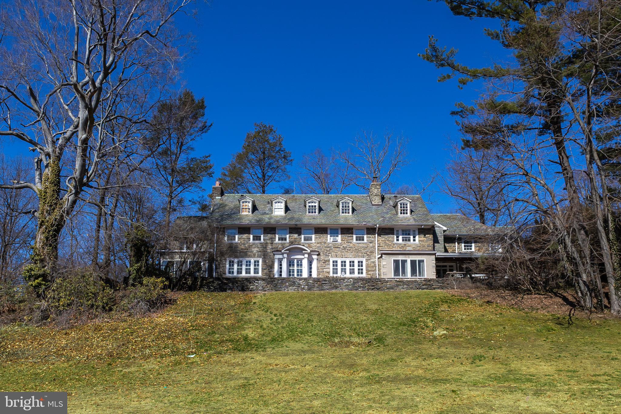 Nestled in the heart of Merion Station, this grand, stone, 7,328 sq ft estate offers endless potential for those looking to create their dream home. Situated on a lush 1.23 lot, the property boasts 8 bedrooms, 6 full bathrooms, and 2 half bathrooms, offering plenty of space for a growing family or hosting guests. The sunny, stately foyer welcomes you from both the front and rear of the home and showcases the exquisite finishes that adorn the home. From here, you will enter the expansive formal living room with a double-sided fireplace that seamlessly leads into a charming four-season sunroom — perfect for year-round enjoyment. Across the entry, the sizeable formal dining room, has a fireplace, and views of the lush grounds, ideal for elegant gatherings both intimate and grand. The spacious kitchen is ready to be transformed into the chef's dream you have always envisioned. The breakfast area offers access to a tranquil, covered slate patio, ideal for al fresco dining. The patio with stone BBQ and built-in seating continues the length of the home overlooking the sweeping backyard. A cozy family room provides a comfortable space for relaxation, while a convenient mudroom with a half bath helps keep things organized. Ascend the beautiful open staircase to the primary suite, a true retreat with a dressing area, a walk-in closet with access to private patio, and a full ensuite bathroom. A second bedroom with full ensuite bath and two more bedrooms sharing two full hall bathrooms and a bonus room complete this level. The third floor adds even more possibilities, with an additional bedroom with full ensuite bath, 3 bedrooms and a full hall bathroom, providing ample space for family or guests. The property also features an unfinished basement, awaiting your finishing touches, and a separate 4-car garage with an upstairs apartment — ideal for rental income, guests, an art studio, au pair, in-laws or a home office. Located within the highly desirable and award-winning Lower Merion School District and walking distance to houses of worship, restaurants, stores, a supermarket, the R5 train, and buses. This estate home is truly a rare find, offering charm and customization potential. Bring your vision to life in this timeless home.