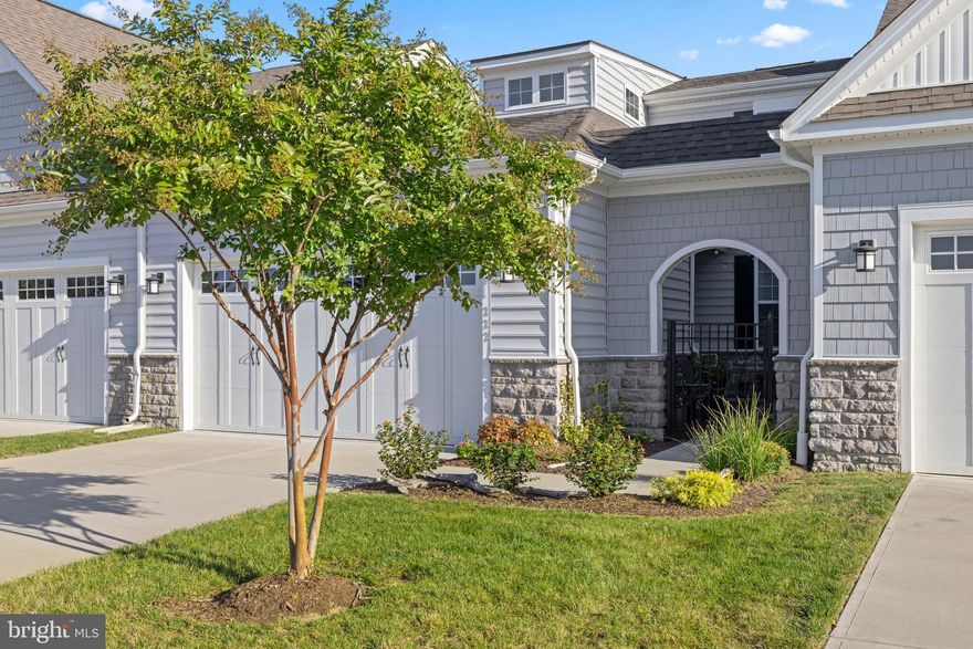 Welcome home to refined coastal living on Maryland’s Eastern Shore in this beautifully designed 3-bedroom, 3-bath home located in the premier 55+ community of Bay Bridge Cove in Stevensville, Maryland.
This lovely and well-maintained home was built in 2022 and offers 2,074 square feet over two levels.  The home blends light-filled spaces with effortless, low-maintenance living just minutes from the Chesapeake Bay.
Soaring cathedral ceilings elevate the main living area, where a propane fireplace creates a warm focal point for entertaining or just relaxing.  The kitchen is designed for gathering, featuring granite countertops, a custom backsplash, stainless steel appliances, and an expansive center island with cabinetry on both sides — ideal for casual breakfasts or evenings entertaining friends and neighbors.  A dining area is located between the kitchen and living area, completing the truly open concept.  Enjoy your morning coffee or curl up and read a good book in the sunroom located just off the living room, featuring lovely views of the tree lined open space at the rear of the home — no neighbors behind you!  The main-level primary suite offers tray ceilings, dual closets, double vanities, and a beautifully tiled walk-in shower — a peaceful retreat at day’s end. A second bedroom and full bath on the main level provide convenience for guests, while the upper level offers a private third bedroom with full bath and a spacious family room with custom railing overlook, perfect for extended stays or additional living space.
Other features of the home include a welcoming gated courtyard with charming bistro lighting, perfect for a little gardening, or unwinding at the end of the day.  Beautiful custom blinds are tailored to each room, ceiling fans are located throughout, and the front and rear storm doors provide even more light into this light and airy home.  The two-car garage has ample space for your vehicles, water toys, or just some extra storage.  The lawn irrigation system helps to maintain a plush lawn, and lawn maintenance is included in the HOA, allowing you to enjoy the community lifestyle Bay Bridge Cove residents embrace. 
Bay Bridge Cove residents settle into a vibrant, resort-style setting with an oversized clubhouse with fitness center, meeting and gathering spaces, full kitchen, community pool, pickleball, and bocce. Activities abound at this gathering spot all year round!  The walking/biking trails are throughout the community, as well as a dog park for your furry family members, and even a community garden for those fresh summer vegetables.
Ideally located just minutes from the Chesapeake Bay, area golf courses, waterfront dining, shopping, and multiple marinas.  Annapolis is a short 15 minutes away, Washington DC is about an hour, and Atlantic Coast beaches are approximately a 2-hour drive.  This home offers the perfect balance of coastal charm, convenience, and active adult living, and is just waiting for you to call this HOME!  Schedule your private tour today!