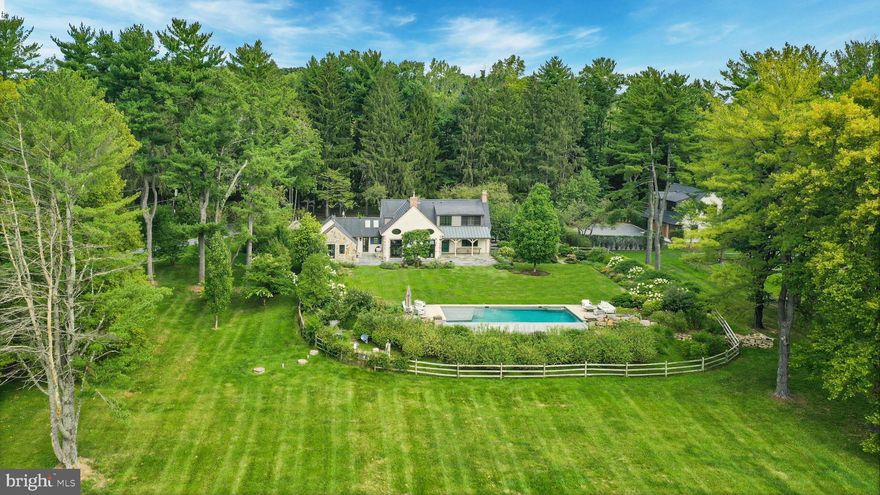 The winding country roads of Solebury Township are an idyllic backdrop for this elegant gated estate. Surrounded by twelve acres of rolling meadows and verdant woodlands, this bucolic property offers a serene and secluded retreat like no other. 

Holmquist Farm epitomizes a harmonious coexistence between nature and the comforts of home. Every aspect of the property has been renewed or improved in the last three years, including stunning new floors and unique light fixtures throughout the main house, a detached garage with luxe guest house, extensive landscaping, infinity pool, and even a pickleball court. 

Entry begins with a classic formal living room with deep silled windows, walls of built-ins, and a wood-burning fireplace. The large family room boasts a 2-story vaulted ceiling with reclaimed wood beams and massive chandeliers, along with a floor-to-ceiling stone fireplace flanked by tall windows. The 2022 gourmet kitchen is a chef’s dream, with marble backsplash, soft close cabinets, burnished bronze fixtures, and a large island. The dining room is elegant with hand painted orchids adorning the walls and French doors leading out to a bluestone patio surrounded by stately rows of flowering trees.

The luxurious first floor primary suite is a private oasis, with a high ceiling, lavish spa bath, and sliding glass doors to an ivy-draped patio. Upstairs, another full bedroom suite includes a built-in window seat, two Juliet balconies, and private bath, while two additional bedrooms share an updated hall bath. The finished lower level delights with a fully equipped wet bar, flex room suitable for a home office or extra bedroom, and wine room. A home theater, full bath, and stairs to the outside make this a wonderful space to entertain family and friends.

The grounds are ideal for entertaining or quiet days at home. Flowering trees and specimen plantings surround the home, while lush grass extends to a heated in-ground saltwater infinity pool with laminar jets. Surrounded by bluestone patios, this scenic overlook offers long-distance views overlooking open farmland and the hills and valleys of Solebury Township.

Across the driveway a newly built detached garage offers four bays with space for five vehicles. The upstairs guest apartment is an elegant residence on its own. An open-plan living area includes a full kitchen, positioned to take advantage of the oversized picture window looking out over the gardens. The custom marble backsplash is a work of art featuring flowering branches with dimensional marble petals. Two sunny bedrooms and a full bath are nearby, as well as a state of the art exercise room featuring a patented hardwood floor with subfloor spring mechanism and Nanawall that opens to the beautiful environs.

The property was once owned by Miss Karline Holmquist, founder of The Holmquist School for Girls, which merged with a local boys school to become the co-educational Solebury School, whose campus is located just up the road. Peace and quiet, a secluded haven within 90 minutes from three major metropolitan cities with access to international airports, world-class arts, cultural amenities, entertainment, shopping, and fine cuisine can all be yours at Holmquist Farm!