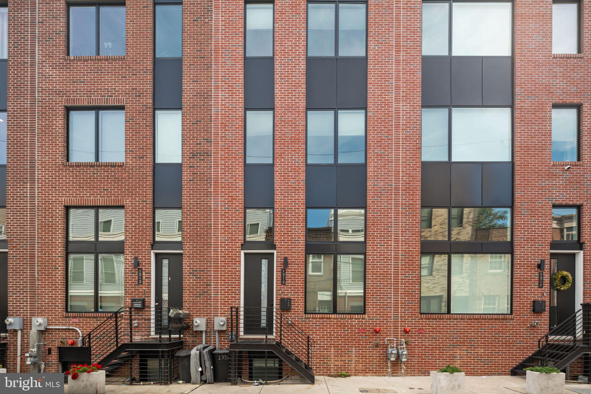 Welcome to 1315 S Capitol St, part of the Wharton Court luxury development in Point Breeze! This stunning 3 bed, 2 & 1/2 bath townhome offers both traditional charm and modern sophistication, featuring a spacious floor plan with 14' ceilings in the main living room, an abundance of natural light, and a private garage that leads directly into your home. The sleek kitchen boasts stainless steel GE Profile appliances, a spacious layout, and overlooks the living room with glass railings, providing an open and airy feel. The owner's suite occupies an entire floor with a spa-like bathroom, including a soaking tub, large shower, and massive walk-in closet. Upstairs, you'll find two more bright bedrooms, a laundry closet, and a dry bar leading to the rooftop deck with breathtaking city skyline views. Located in the heart of Point Breeze, Wharton Court is minutes from Center City, University City, CHOP, and I-76. Enjoy smart home features like thermostats, a door lock, and a video doorbell, all controllable from your phone or tablet! Home has 8 years left on tax abatement! Schedule your tour today