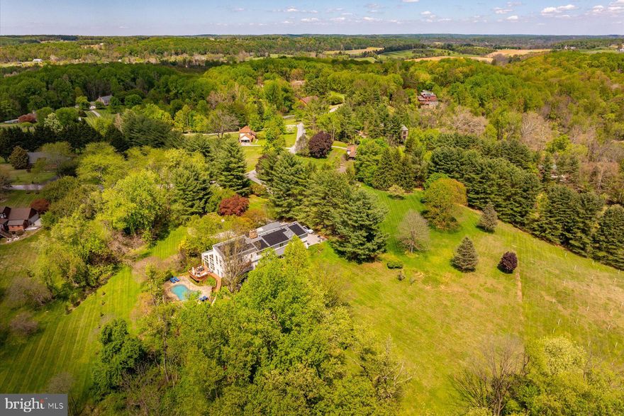This striking contemporary home, set on almost four pastoral acres, features vaulted ceilings, skylights, floating staircases, and walls of windows. The design includes building materials that reflect the natural setting: floor-to-ceiling stacked stone walls and fireplaces, reclaimed wood beams, pine plank floors. With five bedrooms and six full baths, there is ample room to house and entertain family, friends, and guests. The vaulted primary suite has its own deck and a private bathroom that includes an oversized walk-in shower, soaking tub, dual vanity, and fireplace. Three additional bedrooms and two more full baths are spread out across this level. The finished lower level includes another full bath, bedroom, and living room - ideal for an in-law or au pair suite. Highlights on the main level include a vaulted great room with soaring ceilings, natural light, large stone fireplace, wall of built-ins, and access to the largest of several decks. The adjoining kitchen features alder cabinets, soapstone counters, stone backsplash, and stainless appliances. It adjoins an elegant dining room with pastoral views. At the far end of the main floor is a cozy library with custom cherry bookshelves - it too opens to a private deck. Near the library is a cooking studio and office, recently created by converting two of the four garage bays into conditioned space. The cooking studio could be converted into an art or woodworking studio, home gym, family room, or even into separate living quarters. The space has its own outside entrance, opens into the main level, and has convenient access to a full bath. Additional significant improvements include a new roof (2024), all new skylights (2024), and high-efficiency solar panels (2025). Energy savings on the 6,000-plus-square-foot home are estimated to be over $5,000 per year; the solar panels are owned and transfer to a new owner. The property includes a gunite in-ground pool (new cover 2025), six-person salt water hot tub (2025), fenced play area that doubles as a dog run, gazebo, and outdoor space for sport and exploration. There is ample room for vehicles with a two-car garage, parking area, and circular driveway. Enjoy lush landscaping, rolling hills, and the peace and quiet of country living just minutes from Hunt Valley Towne Center, the NCR Trail, Worthington Valley biking, and Oregon Ridge Park. Professional photos and floor plan will be uploaded soon!