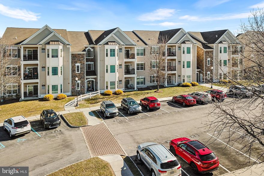 This beautifully maintained 2 BD, 2 BA condo in the sought after 55+ community of Traditions at Ridley Creek offers one floor living, with outdoor balcony space and a lovely view. An open floor plan allows you to entertain or find a cozy spot all to yourself. Once inside you will find a spacious layout with upgraded flooring and tons of natural light.  The gorgeous kitchen features 42" cabinetry with crown moldings, double sink, breakfast bar, tile backsplash and newer GE Appliances with slate finish. The huge primary bedroom offers an en-suite and double closets. A bright second bedroom at the other end of the home shares a hallway with a spacious den outfitted with custom built-in storage cabinets. A full bathroom is also found here. The unit features in house laundry and a utility closet off of the balcony where the newer high efficiency heater and water heater are housed. You will love the views overlooking the woods and creek from the private balcony. Complete with a dedicated storage unit conveniently located in the same building and a private parking spot. This is low-maintenance living at its best in a welcoming, well-cared-for community.