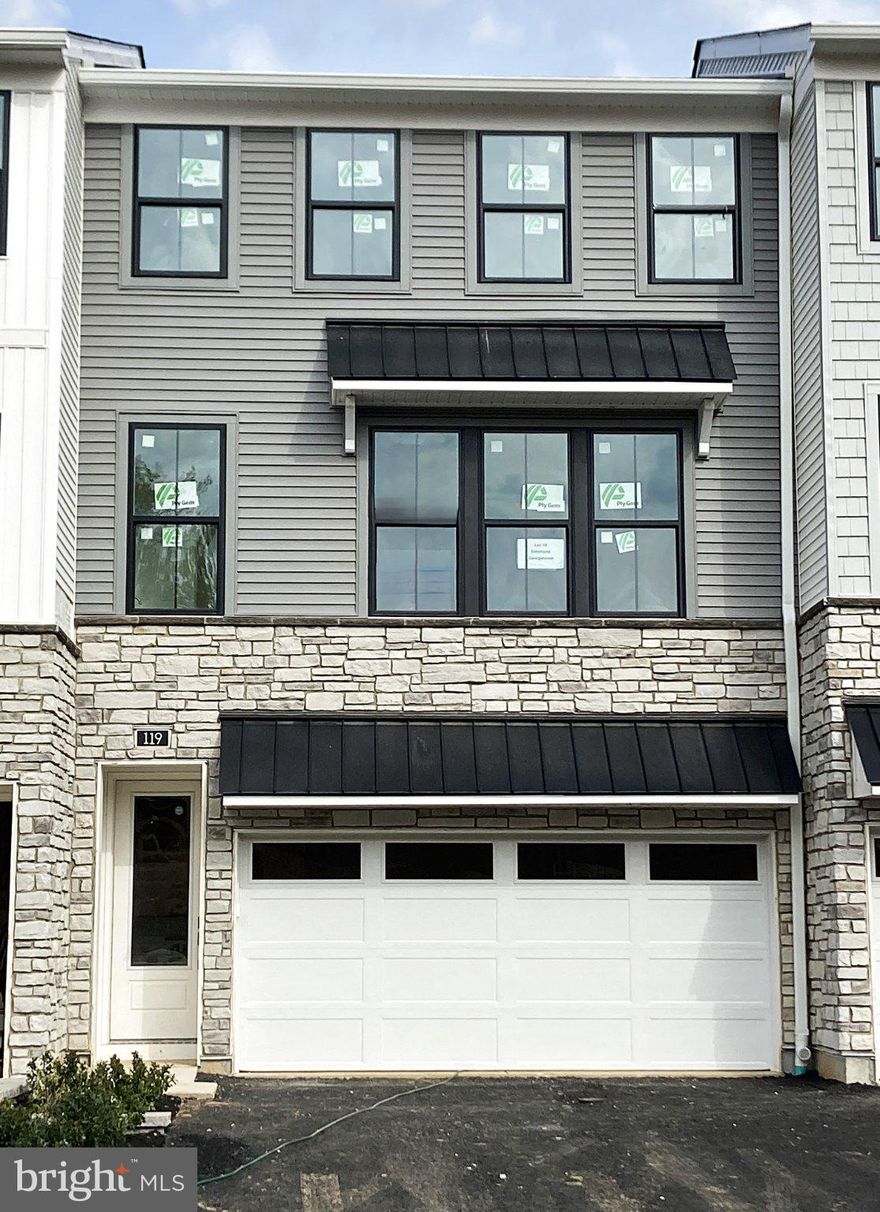 This home is currently under construction and features a thoughtfully planned three-level layout with designer-selected finishes throughout. The entry level includes a welcoming foyer, convenient access to the garage, and functional space designed for everyday living.

The main living level offers an open and airy design highlighted by light-colored luxury vinyl plank flooring and recessed lighting throughout. The kitchen is beautifully appointed with white cabinetry, a pewter-colored island, quartz countertops, and KitchenAid appliances, creating a stylish yet practical space for cooking and gathering. The open flow into the living and dining areas makes this level ideal for both daily use and entertaining.

On the bedroom level, all bedrooms feature plush carpeting for added comfort. The primary suite includes a spa-inspired bath with upgraded tile, Kohler fixtures, a frameless shower enclosure, and a rain shower head for a true retreat-like experience. Two secondary bedrooms share a well-appointed hall bath with upgraded tile finishes. Bedroom-level laundry adds convenience and completes this thoughtfully designed home.

The main living area on the second floor offers an open-concept layout ideal for modern living. A spacious great room flows into a sunlit dining area and a stunning kitchen appointed with white cabinetry, a contrasting pewter-colored island, and quartz countertops. An upgraded tile backsplash and under-cabinet lighting add a touch of elegance, while KitchenAid appliances complete the well-equipped space. Luxury vinyl plank flooring extends through the main living areas, complemented by elegant iron balusters and recessed lighting that enhance the home’s bright, contemporary feel. A deck off the great room provides a seamless indoor-outdoor connection, perfect for entertaining or everyday enjoyment.

Upstairs, the serene primary suite includes dual walk-in closets and a beautifully finished bath with quartz countertops, upgraded tile, and a frameless glass shower enclosure. Two additional bedrooms share a full hall bath with quartz countertops and coordinating designer tile. Thoughtfully selected finishes and convenient bedroom-level laundry complete this stylish and functional home.