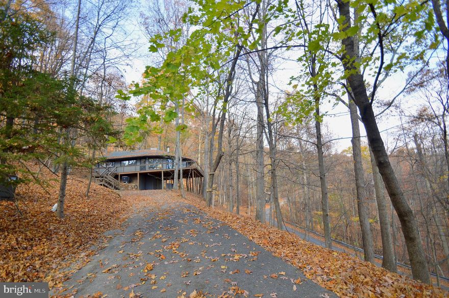 Your modern treehouse awaits!  This one-of-a-kind home features floor-to-ceiling windows with panoramic views, and was renovated down to the studs by the current owner.  Interior improvements include a bright modern kitchen with stainless steel appliances, exposed beams in the 20-foot tall living room ceiling, and hardwood floors throughout.  The master bathroom offers a spa-like atmosphere with marble tile, a custom double vanity, and soaking tub.  A stairway leads to a finished loft area that adds nearly 400 square feet of extra space.  Designer light fixtures and other thoughtful touches add to this mid-century modern gem.  The exterior renovations include a new roof and an expansive deck with stainless steel cables that maximize the views of treetops and nearby mountain ridges.  The mountainside community of Coolfont is less than 10 minutes to Berkeley Springs, but features a community pool and hot tub, hiking trails, tennis courts, and much more.  You will not find another home like this in Berkeley Springs!  A must see!
