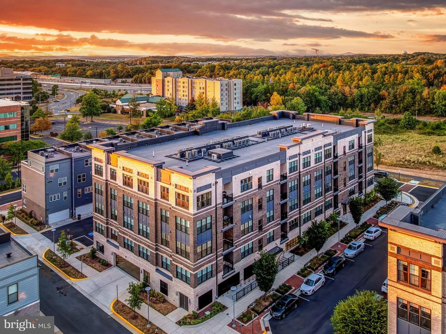 Welcome to 2320 Field Point Drive – a sleek, modern, one-level corner unit condo that checks every box for luxury, convenience, and style, all in a secured access building just a short walk to the Innovation Center Metro Station. This light-filled 2 bed, 2 bath home features a bright open layout with wide plank hardwood floors in the main living areas and plush carpet in the bedrooms. The chef’s kitchen is the centerpiece, with a massive quartz island that comfortably seats four, 42-inch white shaker soft-close cabinets, a gas cooktop, wall oven, WiFi-enabled microwave and range hood, and a modern backsplash that pulls it all together. Both bathrooms offer soft-close vanities with quartz countertops, and the spa-like primary bath includes a seamless glass shower, dual vanities, quartz tops, and a built-in bench. The spacious primary suite easily fits a king-sized bed and includes a walk-in closet. Additional highlights include a dedicated laundry room with front-load washer and dryer, a tankless hot water heater, recessed lighting throughout, and a covered balcony perfect for relaxing. The condo comes with one assigned garage space, one surface parking space, and plenty of guest parking. You’ll also enjoy access to community amenities like tennis courts, basketball court, soccer field, jogging paths, picnic areas, a playground, and a fully fenced dog park just one block away at Arrowbrook Park. A well-lit, landscaped walking path with benches and archways leads directly to the Innovation Center Metro Station in about 12 minutes and also connects to Downtown Herndon. Just steps from shopping and dining at Village Center at Dulles and Clock Tower Shopping Center, and minutes to Reston Town Center, Dulles Airport, and the exciting upcoming Rivana development. FHA and VA approved. This is modern condo living at its best—don’t miss it! Condo fee includes water, sewer, trash, snow removal.