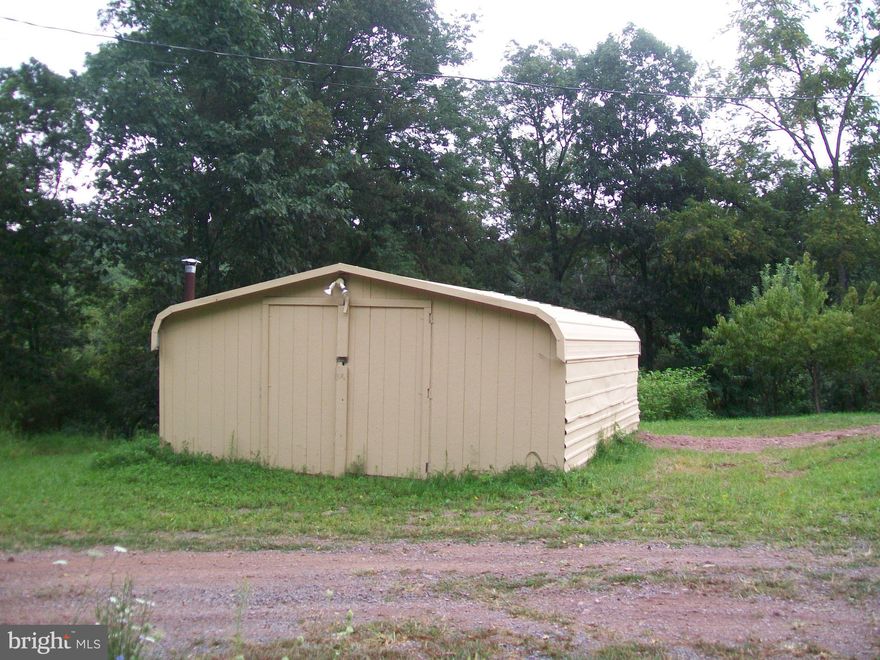 Great spot at the end of the road.  Freshly improved with on-site electric.  Well and septic already in place.  Level  area freshly graded and ready for your camper, RV, or mobile home.  Or build your get-away cabin or permanent home.  One outbuilding - small garage.  Property is buffered by trees on two sides and flowering bushes in the front and even has 3 fruit trees - apple, peach, and cherry.   Very private.