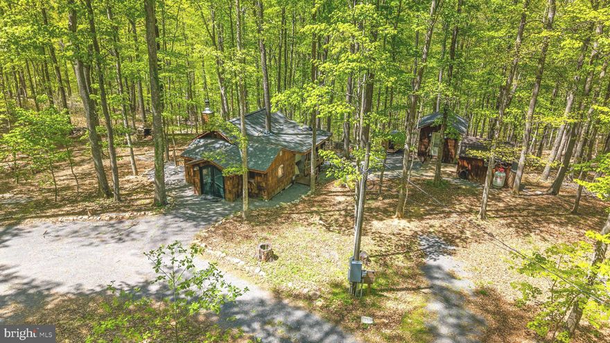 PROPERTY COMES FULLY FURNISHED AND READY TO GO!!!! Welcome to your Private Retreat,  a truly unique and artfully crafted one-bedroom, one-bath cabin tucked away on 6.23 private acres in the heart of Almost Heaven, West Virginia. Surrounded by 150+ year-old old-growth hardwoods, including oak, maple, ash, poplar, and hickory, this magical retreat offers unparalleled peace, beauty, and privacy.  This cabin showcases exceptional craftsmanship using thoughtfully selected reclaimed materials, bottle brick window transoms, and a wrap-around porch incorporating live trees. Enjoy evenings around the outdoor fireplace built from native stones or soak in the views from your hot tub and barrel sauna. River access to one of the best swimming holes in the region adds to the outdoor charm. Interior & Features Include a fully furnished and professionally designed interior, Hot tub (2024) and barrel sauna (2023), Mini-split HVAC systems in both cabin and a separate custom bathhouse, an upgraded tankless water heater (2024), new dishwasher and oven. Also, a Level 2 EV charger, you just need the cable, fiber optic internet with mesh WiFi, SmartLock system, security cameras, outdoor shower, DSL backup, and designer furnishings throughout.  Whether you’re looking for a private retreat, an artist’s haven, or just a weekend getaway, this is the cabin you’ve been waiting for. All appliances, grill, hot tub, and sauna are included, and furnishings can be conveyed for a seperate amount. (Excludes linens, towels, tools in shed, and items labeled with the property name or logo.). Don’t miss the chance to own a piece of Appalachian paradise. NO SHORT-TERM RENTALS! Note, the full bathhouse is on the outside of the property.