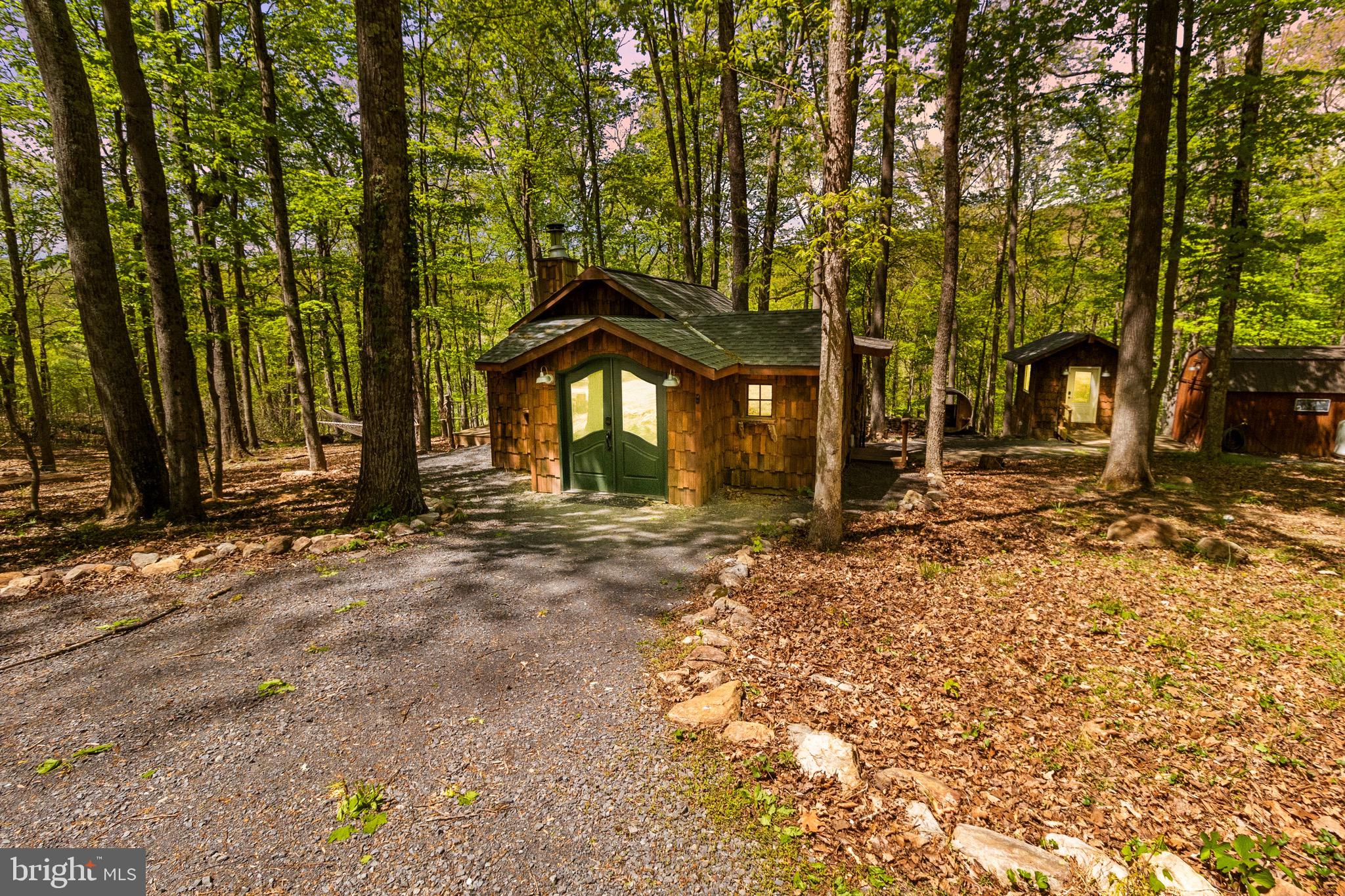 Welcome to your Private Retreat — a truly unique and artfully crafted one-bedroom, one-bath cabin tucked away on 6.23 private acres in the heart of Almost Heaven, West Virginia. Surrounded by 150+ year-old old-growth hardwoods including oak, maple, ash, poplar, and hickory, this magical retreat offers unparalleled peace, beauty, and privacy. This cabin showcases exceptional craftsmanship using thoughtfully selected reclaimed materials, bottle brick window transoms, and a wrap-around porch that incorporates live trees. Enjoy evenings around the outdoor fireplace built from native stones or soak in the views from your hot tub and barrel sauna. River access to one of the best swimming holes in the region adds to the outdoor charm. Interior & Features Include a fully furnished and professionally designed interior, Hot tub (2024) and barrel sauna (2023), Mini-split HVAC systems in both cabin and separate custom bathhouse, upgraded tankless water heater (2024), new dishwasher and oven. Also, a Level 2 EV charger, you just need the cable, fiber optic internet with mesh WiFi, SmartLock system, security cameras, outdoor shower, DSL backup, and designer furnishings throughout. Whether you’re looking for a private retreat, an artist’s haven, or just a weekend getaway, this is the cabin you’ve been waiting for. All appliances, grill, hot tub, and sauna are included, and furnishings can be conveyed for a seperate amount. (Excludes linens, towels, tools in shed, and items labeled with property name or logo.). Don’t miss the chance to own a piece of Appalachian paradise. The seller will need a long settlement to accommodate previous reservations. NO Short-Term rentals.