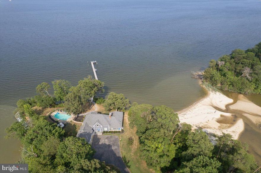 PATUXENT RIVER WATERFRONT TRIFECTA: Pool, pier & beach access!! Get excited about this lifestyle property with a gorgeous updated three level home on a 3.4 acre point of land with 900+ ft of shoreline on both Esperanza Pond and the Patuxent River. Experience waterfront living at its finest with a remarkable 300+ ft pier that sets this property apart. Ideal for boating enthusiasts, the pier features a convenient jet ski lift equipped with a remote control for effortless access to the water. Whether you're fishing, enjoying water sports, or simply soaking in panoramic views of the tranquil surroundings, this pier is a quintessential feature that enhances the allure of this exceptional waterfront retreat. Dive into relaxation and enjoy resort-style living with this stunning waterfront inground pool with depths ranging from 3 to 10 feet, perfect for both lounging and swimming. The chlorinated pool is equipped with a diving board as well as a new, sleek hardcover LoopLoc for added safety and maintenance ease. The private path to the adjacent beach is a highly prized aspect of this lot, and is a feature you will not want to miss! Upon arrival, you'll note a private drive to the entrance of this thoughtfully updated home with Hardie siding and blue stone front porches. Enter the home and experience views through to the Patuxent River. The central living space with beamed ceiling and built-ins adjoins the dining area, which then connects to the main level outdoor living area. The entry level primary suite wing delivers dramatic high wood ceilings and more water views, a deluxe bath with dual sinks + spa tub & custom tiled shower and owner’s laundry service.  Prepare beautiful meals and enjoy views of the river and in ground pool from the chef’s kitchen with 48” dual fuel range, extensive granite counters atop custom Miller cabinetry-all with an intimate connection to the family room. Enjoy breathtaking views of the serene water vistas through the picture windows, flooding the space with natural light and creating a seamless indoor-outdoor connection.  More exciting features include two brick fireplaces, walk-in pantry, half bath near the pool with custom mud room design, gorgeous tiled bathrooms and abundant water views from all levels. The upper level includes two bedrooms with superb river and pool views. They share an adjoining custom tiled shower bathroom, plus access to a large walk-in attic storage over the garage wing. The lower walkout level is modern with all split system HVAC, two more bedrooms and a covered patio just steps to the pier, a third full bath, recreation space with brick fireplace. This new space is perfect, with tile floors and big water views! Envision a wine room, have second laundry service. This residence has the premium lifestyle features we find in many properties individually…but rarely do we see the combination in a single offering.