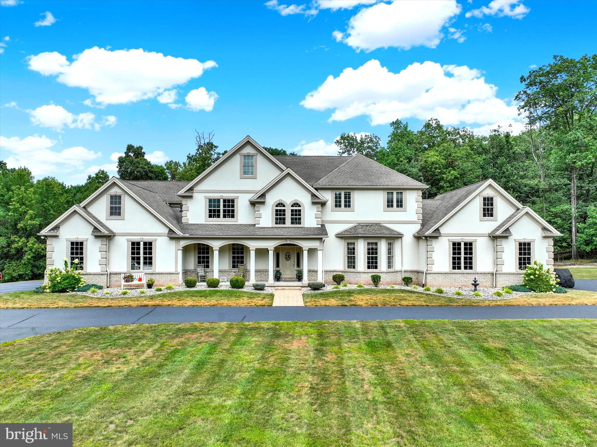 Welcome to a residence of timeless elegance and distinction. This extraordinary custom-built estate boasts over 6,000 square feet of refined living space, gracefully positioned on 58 acres of pristine, scenic countryside. A true sanctuary, the property evokes the feeling of a private resort—an enchanting retreat where luxury meets tranquility. While offering unmatched privacy, the estate is ideally located within easy reach of York, Harrisburg, Lancaster, and Gettysburg, with the Maryland line just 20 minutes away.
The experience begins the moment you travel up the stately, tree-lined drive, leading you toward a sense of anticipation. As the driveway opens, a magnificent estate reveals itself—an architectural masterpiece set amidst a private sanctuary of unmatched beauty. Impeccably manicured grounds frame the residence, offering a breathtaking backdrop that is both serene and inviting. On warm days, an exquisite inground pool provides the perfect retreat, while at night, you can float under a canopy of stars, surrounded by the tranquility and elegance of this exceptional property. Picture a peaceful Saturday morning with coffee in hand, listening to the gentle sounds of nature, and savoring the unparalleled sense of serenity this remarkable estate affords.
Designed with both elegance and functionality in mind, this distinguished residence features two attached two-car garages, artfully positioned at each end of the home to enhance its architectural grandeur. A generously sized cement parking area offers the ideal space for campers, boats or work trailers.
This extraordinary residence reveals itself as a masterpiece of timeless design and modern elegance Spanning across three levels of finished living space. This exquisite estate offers 4 bedrooms, 3 full baths, and 2 half baths which seamlessly blends sophistication with comfort across three thoughtfully designed levels. A grand two-story foyer sets the tone with its sweeping staircase, intricate wainscoting, and streams of natural light cascading through dramatic transom windows. Formal entertaining is elevated in the distinguished dining room, where a tray ceiling, refined crown molding, and a stately fireplace create an ambiance of warmth and grace. The expansive living room, crowned with a coffered ceiling and framed by walls of windows, invites both intimate gatherings and grand entertaining, its fireplace providing the perfect centerpiece. At the heart of the home, the gourmet kitchen is a culinary sanctuary, offering bespoke cabinetry, professional-grade appliances, and an oversized island designed for both function and beauty. A sun-drenched breakfast room opens onto the terrace, blending indoor and outdoor living with effortless elegance. A main-level powder room and expansive laundry/mudroom enhance the home’s thoughtful design. Ascending upstairs, the primary suite redefines luxury living. A private sitting area, its own fireplace, and French doors to a secluded balcony create a serene retreat. This luxurious suite is enhanced by 2 full baths: his and her full bathrooms, each with their own walk-in closet, ensuring comfort, privacy, and sophistication. Additional bedrooms are generously sized and supported by well-appointed bathrooms, offering both style and practicality. The lower level extends the home’s lifestyle amenities with multiple versatile living spaces, ideal for recreation, fitness, or gatherings. A handsome fireplace adds ambiance, while a stylish half bath completes the space. The dedicated fitness room may also serve as the perfect home office or private study, offering flexibility to meet the needs of today’s lifestyle.
In total, this exceptional estate offers four fireplaces — in the living room, dining room, primary suite, and lower level — infusing warmth and sophistication throughout. Every detail, from the custom millwork to the expansive windows and architectural artistry, speaks to the home’s uncompromising quality.