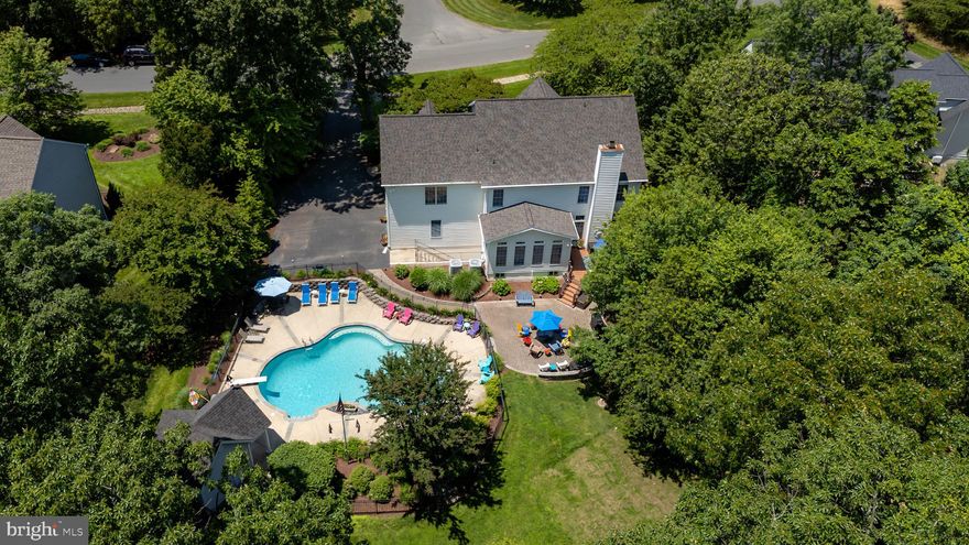 Discover this spectacular 3-level Contemporary nestled in the Riding Woods Community, boasting over 5,920 finished square feet and situated on nearly 1 acre. Expanding front porch and main entrance, featuring a two-story foyer, warmly welcomes guests. French doors lead into the formal living room, while a spacious office with built-in desk and shelving provides an ideal workspace. The formal dining room connects to a butler's pantry, which flows into the gourmet kitchen, complete with a large island, granite countertops, and stainless steel appliances. The light-filled breakfast room features vaulted ceilings and a slider that opens to the outdoor entertainment area. The sunken family room boasts a cozy wood burning fireplace with a floor-to-ceiling stone surround and built-in bookshelves. 
The two-sided staircase provides access to the second floor, where the luxurious Primary Suite boasts a tray ceiling, two spacious walk-in closets, and a serene Primary Bathroom featuring, large soaking tub & walk-in shower, and double granite vanity. Three additional large bedrooms, a full bathroom (connects to one Bedroom and hall), a spacious media/recreation room, and a laundry room and walk in closet complete the upper level. 
The lower level includes a finished basement with a wet bar, full bathroom with steam shower, recreation area, projector TV, surround sound, cozy gas fireplace, and walk-out access to the backyard. Additional features include a large storage/mechanical room and a storage/wine room. The outdoor entertainment areas are highlighted by an inground heated pool surrounded by iron fencing, a pool house with half bathroom, Trex deck, and paved patios.  Gorgeous Landscaping, Oversized two-car garage and paved driveway.  Underground irrigation system and electric dog fence are added bonus. The property backs up to trees and a stream, offering a serene natural setting.  
Also conveniently located near Downs Park, situated on the Chesapeake Bay, which offers 236 acres of nature and recreational activities, including hiking and biking trails, picnic areas, dog beach, bay overlooks, fishing pier, and more. Square Footage based on Public Tax Record, Buyer to verify