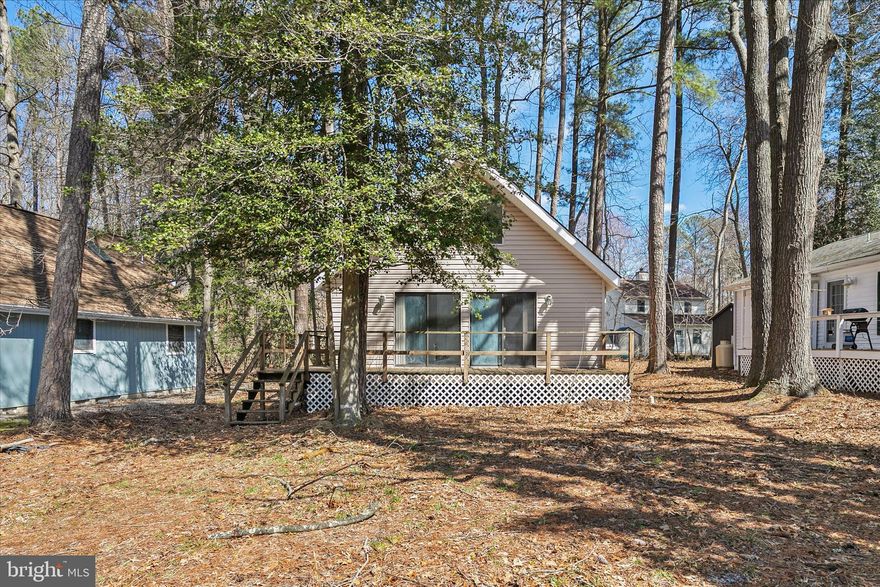 Tucked among the trees in Angola by the Bay, this charming A-frame home offers the perfect blend of coastal living and wooded tranquility. A spacious wraparound deck spans the entire width of the home, creating an ideal setting for relaxing, entertaining, and enjoying the peaceful natural surroundings.

Inside, the inviting living room features a cozy wood-burning fireplace nestled in the corner, while an exposed wood beam adds warmth and architectural character overhead. Two sliding glass doors open seamlessly to the deck, and oversized windows above flood the space with natural light while framing serene treetop views. The open-concept kitchen and dining area connect effortlessly to the living space, enhancing the home’s airy, connected feel.

The first floor offers two comfortable bedrooms, a full bath, and the convenience of a stacked washer and dryer tucked neatly into a closet. Upstairs, a spacious loft-style bedroom with a half bath overlooks the main living area and showcases dramatic A-frame windows at the peak offering stunning elevated views of the surrounding woods.

Located in the amenity-rich community of Angola by the Bay, residents enjoy access to a clubhouse, marina, sports courts, horseshoe pits, picnic pavilion, kayak storage, walking trails, playground, baseball field, and a beautiful in-ground pool with an outdoor fire pit. Ideally situated on Burton’s Prong and just minutes from Lewes, Rehoboth Beach, and Route 1’s dining and shopping, this home offers both convenience and coastal charm.

Ideal as a primary residence, vacation getaway, or investment opportunity being sold As-Is.  Any remaining furniture is included.  Don’t miss your opportunity to own your own private retreat by the bay.