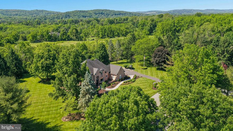 In the enviable neighborhood of Deer Run at the end of a quiet cul-de-sac, privately positioned on 1.8 acres, this all-brick custom Myron Haydt home has ageless appeal and boasts a totally redone Widell and Boschetti designer interior that should grace the pages of a magazine. Mature landscaping envelopes the property offering southern exposure, seasonal views of mountains, and a coveted Saucon Valley location.
An amazing recent renovation showcases custom modern finishes and newly designed open spaces. The grand two-story foyer has a marble floor and curved staircase. Open and filled with light, the floor plan surprises. A first floor office opens to the foyer through French doors.  Windows in every room bring the outside in and offer perfect privacy without the need for window treatments. With every new amenity and family feature, entertaining will be a delight. 
The gourmet kitchen and adjacent family room with soaring 13 foot ceiling lead to incredible outdoor spaces where brick and bluestone patios provide a relaxing oasis amid well-tended plantings and visiting songbirds. A sumptuous primary bedroom suite, with two walk-in closets, octagonal tray ceiling, and access to the private yard is conveniently located on the main level. The new and exquisite primary bath will take your breath away. Three additional bedrooms, bonus room, and two full baths comprise the second floor, while a finished lower level is fully equipped with bar, exercise room, full bath, and future theatre room. Recent HVAC system upgrades will ensure the integrity of this impeccably cared for home. 
Interstate 78, Saucon Valley Country Club, St. Luke’s Hospital and the Promenade Shops are accessed, within minutes, from this distinctive and timeless home.