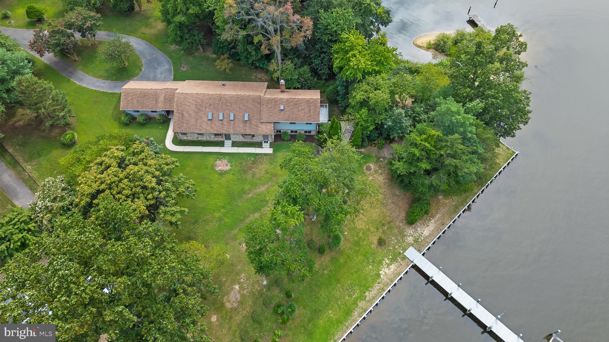 A rare and extraordinary opportunity to own 1.53 acres of premier waterfront on a private point with sweeping views of Bodkin Creek and easy access to the Chesapeake Bay. This remarkable property features over 500 feet of shoreline along both Bodkin Creek and Jubb Cove, offering riparian rights, a blend of bulkhead and natural shoreline. The 80-foot pier on Bodkin Creek provides 10+ MLW, electric, water, and a boat lift, while a secondary 45-foot pier on Jubb Cove expands your waterfront access. Adding to its allure, the property offers both walkable and vehicular access to your own private sandy beach—a rare and coveted feature perfect for launching kayaks, relaxing by the water, or simply soaking in the tranquil surroundings. The residence is a spacious 3-bedroom, 2.5-bathroom bi-level home offering over 3,000 square feet of finished living space. The main level welcomes you with a generous living room that opens to the dining area and kitchen, accented by vaulted ceilings, exposed beams, and skylights. Two bedrooms and a full bath complete this level, while the upper-level primary suite features a private balcony and an expansive ensuite bath. The lower level offers a large clubroom with a fireplace and wet bar, ideal for entertaining. A breezeway connects the home to a two-car garage. Whether you envision updating the existing home or designing a custom waterfront retreat, the setting and scale of this property offers multitude of potential. Located in the sought-after community of Cedarwood Cove, with access to a community pool, pavilion, park, waterfront on Bodkin Creek, and an active swim team, this offering represents a truly rare chance to own one of the most unique waterfront parcels in Pasadena. Community amenities are offered through a voluntary association with payment of dues to join the association.