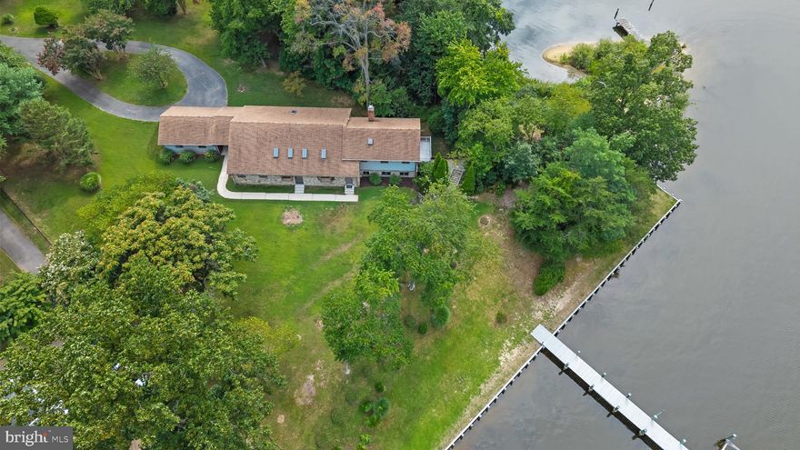 A rare and extraordinary opportunity to own 1.53 acres of premier waterfront on a private point with sweeping views of Bodkin Creek and easy access to the Chesapeake Bay. This remarkable property features over 500 feet of shoreline along both Bodkin Creek and Jubb Cove, offering riparian rights, a blend of bulkhead and natural shoreline. The 80-foot pier on Bodkin Creek provides 10+ MLW, electric, water, and a boat lift, while a secondary 45-foot pier on Jubb Cove expands your waterfront access. Adding to its allure, the property offers both walkable and vehicular access to your own private sandy beach—a rare and coveted feature perfect for launching kayaks, relaxing by the water, or simply soaking in the tranquil surroundings. The residence is a spacious 3-bedroom, 2.5-bathroom bi-level home offering over 3,000 square feet of finished living space. The main level welcomes you with a generous living room that opens to the dining area and kitchen, accented by vaulted ceilings, exposed beams, and skylights. Two bedrooms and a full bath complete this level, while the upper-level primary suite features a private balcony and an expansive ensuite bath. The lower level offers a large clubroom with a fireplace and wet bar, ideal for entertaining. A breezeway connects the home to a two-car garage. Whether you envision updating the existing home or designing a custom waterfront retreat, the setting and scale of this property offers multitude of potential. Located in the sought-after community of Cedarwood Cove, with access to a community pool, pavilion, park, waterfront on Bodkin Creek, and an active swim team, this offering represents a truly rare chance to own one of the most unique waterfront parcels in Pasadena.  Community amenities are offered through a voluntary association with payment of dues to join the association.