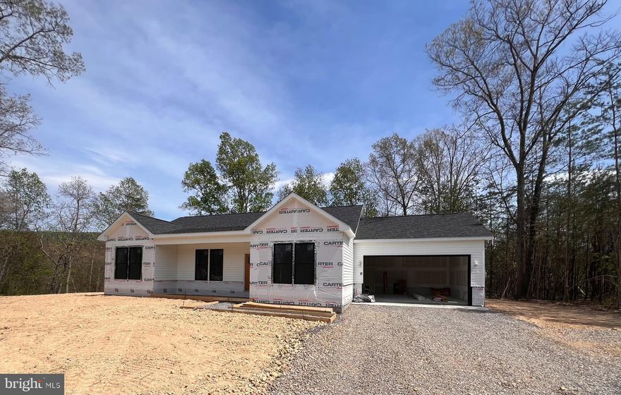 This newly built home offers a rare blend of modern comfort in a peaceful setting—an ideal retreat from the pace of everyday life.  Located on 5.11 wooded acres, this single-level home features approximately 1,600 finished square feet of living space and is thoughtfully designed with a layout that features 2 x 6 exterior walls, 3 bedrooms, 2 full baths, and a separate laundry room for added convenience. Rich 4" solid hardwood flooring flows throughout the main living areas, including the bedrooms, adding warmth and timeless appeal. Ceramic tile adorns the bathrooms and laundry room for easy maintenance.  The kitchen is equipped with sleek stainless steel appliances, and the living room offers a vaulted ceiling to create a contemporary space ready for everyday living and entertaining. Just beyond the kitchen and dining area is the rear deck where the sights and sounds of nature take center stage—perfect for morning coffee, evening unwinding, or simply taking in the quiet beauty of the surrounding woods. A full, unfinished walkout basement with a full bath rough-in provides excellent potential for future expansion—whether you envision additional living space, a recreation area, or a private workspace. The insulated two-car garage offers enhanced protection against the harsh winter cold, thereby enhancing both convenience and functionality. Ideally located, this property offers the feeling of being “away from it all,” while still maintaining accessibility—approximately 30 minutes to Winchester, VA, Martinsburg, and Cacapon Resort State Park. Surrounded by natural beauty and set in a serene environment, this home delivers the balance of privacy, space, and modern living that you're searching for.  So, if you’ve been dreaming of a place where you can relax, recharge, and enjoy the outdoors—this is it.