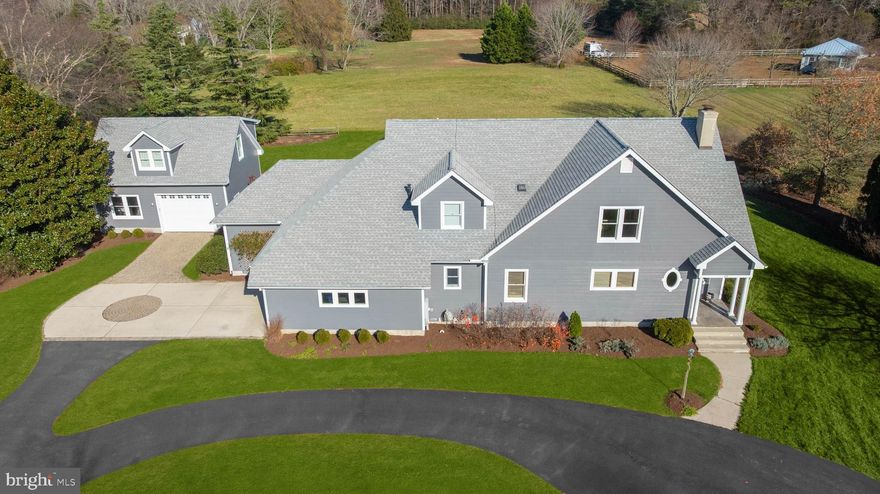 Tucked away on a quiet, tree-lined street in the sought-after Cripple Creek community, this custom-built home offers a rare blend of privacy, craftsmanship, and timeless design.  Situated on a spacious lot with open meadow views and a wooded backdrop, the setting creates the feeling of having no neighbors - just peaceful, natural surroundings.  Designed by acclaimed architect Robert Stern and inspired by the Life Magazine American Dream House, the home was thoughtfully constructed with enduring quality and attention to detail.  The floor plan balances comfort and function, featuring a private first-floor primary suite with a spa-inspired bath, walk-in closet, and custom built-ins, along with a dedicated home office and inviting gathering spaces.  At the heart of the home, the great room showcases a Rumford fireplace - an elegant, historically inspired design - paired with handcrafted detailing and French doors that open to an expansive 13’ x 40’ covered porch. The seamless indoor-outdoor flow continues to a paver patio with hot tub hookup and outdoor shower, ideal for relaxing or entertaining.  The chef’s kitchen is equally impressive, featuring a Viking gas range with custom hood, Sub-Zero refrigeration, custom cabinetry, and a bright breakfast nook.  Additional highlights include a second-floor entertainment room with wet bar and refrigerator, perfect for guests or flexible living. Built for efficiency and comfort, the home is equipped with geothermal heating and cooling, a tankless hot water system, central vacuum, and a whole-house sound system. Recent updates include new HVAC components (2020), exterior paint (2023), and a certified septic system (2025). Car enthusiasts, hobbyists, or those in need of extra space will appreciate both the attached two-car garage and a detached garage with workshop, 250-volt service, and a finished recreation room above. Located in a unique, horse-friendly neighborhood with access to nearby routes and coastal amenities, this exceptional property offers the perfect combination of tranquility, convenience, and refined coastal living.  A Farmette community.  Livestock & stables are permitted.  Total annual energy costs $2,288 (2025).  Total annual property taxes $1,380 (2025).   2019 Cub Cadet zero-turn mower with a 54" deck conveys with the property.