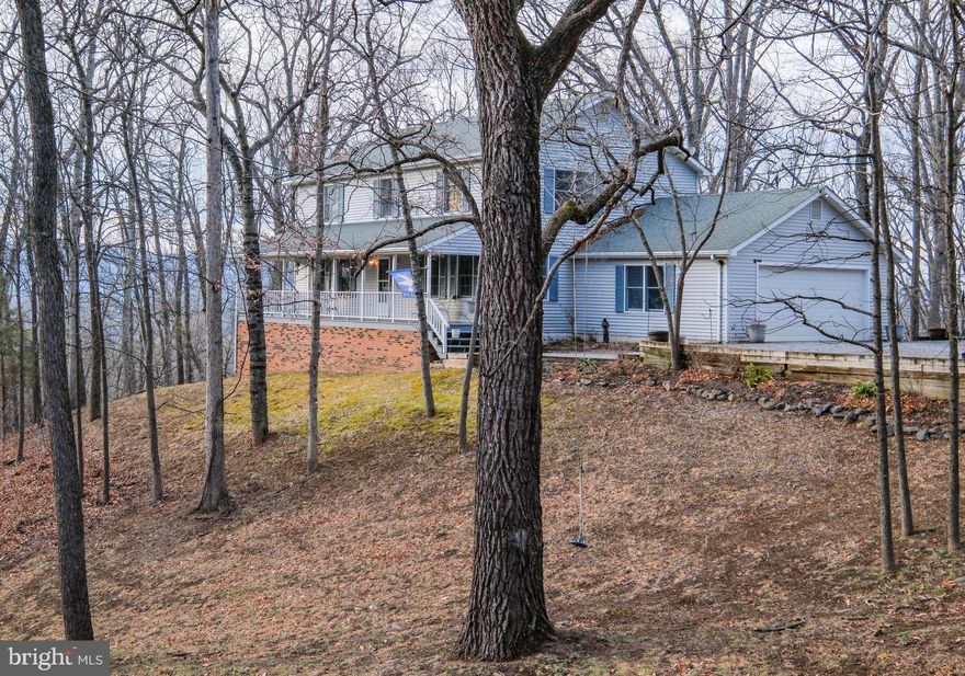 This nearly 2,400 sf remarkably PRIVATE & PEACEFUL four bedroom “treehouse” (with 2 car garage and full unfinished walkout basement offering a potential 1,100+ finished sf) is situated on 5 VIEW-FILLED acres (Shenandoah River and Blue Ridge Mountain views from nearly every window). This setting truly feels like a fairy tale and it is no wonder why the seller calls the property her “treehouse” (she custom built it to capitalize on views and privacy yet provide easy access).  Located just 1 mile down Browntown Road, the nicely paved little-known Cardinal Wind Drive (yes, birdwatchers will delight) boasts only two houses (the other home is at the far end and can’t be seen) and is tucked at the base of the Shenandoah National Park with nature as its neighbor. This property is approximately 3 MILES FROM EVERYWHERE (Shen River access, shopping, schools, historic downtown Front Royal, Eastham river trails/playground/dog park, library) and 8 easy miles from I-66 exit 13 (Linden). No need to drive up a mountain or 20 minutes outside of town to access this home!  And no need to spend hours every weekend on a lawn tractor! This tree-filled property still offers several delightful mossy yard areas (to include a spot with a delightful tree swing) and spectacular sunsets from the 24x12 rear deck (that has extra wide steps that lead to a walkway to the generous parking area off the lovely driveway. FANTASTIC FLOORPLAN–enjoy the 42 foot long front porch (with swing), the gigantic formal living and dining rooms, the view-filled family room off the huge kitchen, the spacious main and upper foyers (main level has a half bathroom off center hallway), the 4 bedrooms/2 huge bathrooms on the upper level, the roomy laundry/mud room (with pantry and utility sink) off the kitchen and garage.  VIEWS FROM ALL ROOMS! The primary bedroom offers a large owner’s bathroom area.  The second oversized bedroom has convenient access to the fourth bedroom (would make a great home office). FEATURES TO NOTE: Brick fireplace (converted to propane w/blower for added heat), Rough in plumbing in basement for a future full bathroom, Conveying washer/dryer, Storm door from garage to house, Pull-down attic steps w/ flooring and fan, Storage under deck, Conventional septic, High speed internet, Deep closets, Hardwood floors (living room, dining room, staircase), Attractive plank flooring in family room/kitchen/foyers, Corian counters (added in 2017), 4-person breakfast bar, Pull-out cabinetry, Built in desk area in kitchen, Picture window w/winter views of river, Ceiling fans (in 3 bedrooms, family and living rooms), Chair railing, Double sinks in huge hall bath (that also has a built in seated makeup area and linen closet), Home warranty offered!  EXTRAS: Heat pump replaced (2018) and maintained twice a year since by Aire Serv, New pressure tank and hot water heater in 2023, Some replacement windows/doors (2021 & 2023 including Anderson sliders to rear deck and more. BOTTOM LINE, ACT QUICKLY SO YOU CAN HAVE YOUR FAIRY TALE BEGINNING ON CARDINAL WIND DRIVE IN 2026 (right in time for the red buds to bloom throughout the property)! PHOTOS CANNOT DUE THIS PROPERTY JUSTICE!