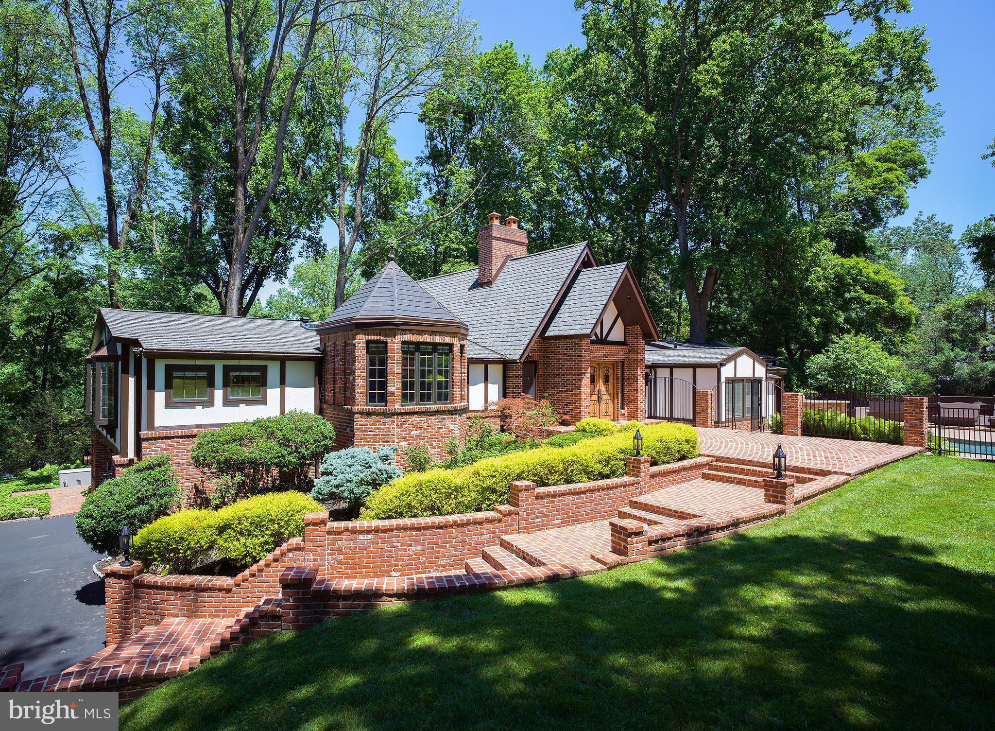 Live, work, play and entertain in this 5 bedroom 5.1 bath gem on a low-traffic cul-de-sac in a prime Villanova neighborhood. The house is impeccably situated on a spacious lot, providing complete privacy with stunning views of lush terraced landscaping & magnificent trees. There is generous parking for guests & tremendous outdoor space on resort-like grounds with a basketball sports court, flat lawn for ball playing, multiple outdoor patios/seating areas, outdoor kitchen with island, outdoor dryer, gas fire pit & amazing salt water swimming pool with waterfalls & spa. Inside is as expansive & gracious with an open floorplan where rooms flow seamlessly; yet there are plenty of private spaces for all. Double entry doors with metal hardware speakeasy windows open into the vaulted Reception Hall with granite & hardwood floors. Off the foyer sits a wet bar featuring a custom wood bar with seating, under-counter fridge/freezer with ice maker, granite-topped sink area, shelving & skylight, as well as a sky-lit powder room. The dramatic living room with a floor-to-ceiling glass wall has a wood-burning fireplace, surround sound for watching sports & movies + a soaring 22 ceiling. The adjacent dining room overlooks the outdoors through a large bow window with built-in cabinetry & marble counter for food service. Your dream kitchen is styled with decorative ceiling beams, cherry cabinets, a center island with seating, granite counters, tumbled marble backsplash with mosaic inlay, large walk-in pantry, top-of-the-line appliances, beverage center with wine storage & command center/workstation with desk. Inside the turret off the kitchen is a den with vaulted ceiling, decorative beams, bay window & surround sound. Enjoy coffee in the large breakfast area with built-in buffet & bay window. Work from home in the richly-paneled library with built-in desk & shelving. The blissful master suite wing is a luxurious retreat with a vaulted ceiling, wood-burning fireplace, marble spa bath, his/hers walk-in closet, dressing area with makeup vanity & vaulted exercise/sitting room overlooking the pool oasis. Private stairs lead to an au pair/in-law suite with a separate outside entrance & kitchenette. The spacious lower level offers a huge playroom adjacent to a family room with a gas fireplace, wall of windows, and doors to the brick terrace. Newer HVAC units, a convenient generator, and great neighborhood near amenities make the lifestyle complete.