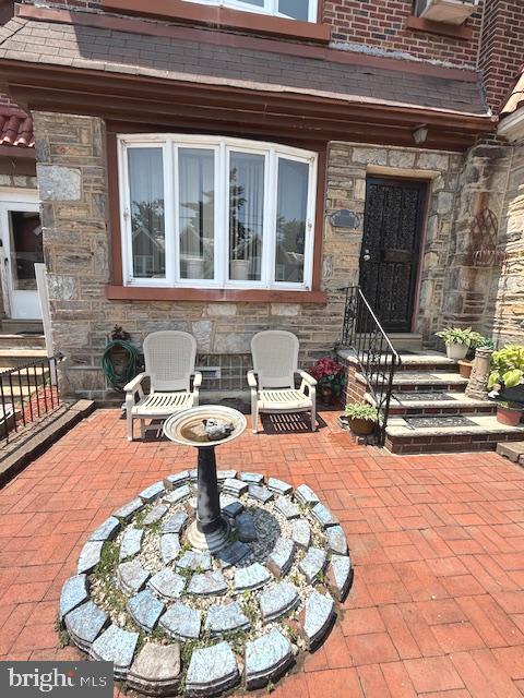 This charming Stone and brick townhouse has lovely hardwood floors and a welcoming layout with three bedrooms, one full bath and one half bath. Initially you will be welcomed by the fenced paver terrace out front with garden features, hose and slate steps. Come through the brand new front door into a giant living room with space for entertaining, gleaming hardwood floors and can lights. From there enter into the spacious dining room graced with a chandelier and more hardwoods. The kitchen has a new gas stove, garden window , pendant lights and counter seating. Beautiful wood steps lead you upstairs to the huge main bedroom with a chandelier and 2 closets. In the hall is an updated 4 piece ceramic tile bathroom featuring a skylight, tub, stall shower, toilet and vanity. Nice sized 2nd and 3rd bedrooms complete the second level that has hardwood floors well. In the fully finished basement there is a laundry area with sink, large half bath with ceramic tile, double sinks and lots of cabinets. In addition to that there is a large family room with french doors to a brick walled paver patio that has a locking door to the alley. Truly an oasis of privacy and peace. Roof replaced 2024. You do not want to miss this great move in ready home! Half of a block to Cheltenham ave. providing easy access to public transportaion.