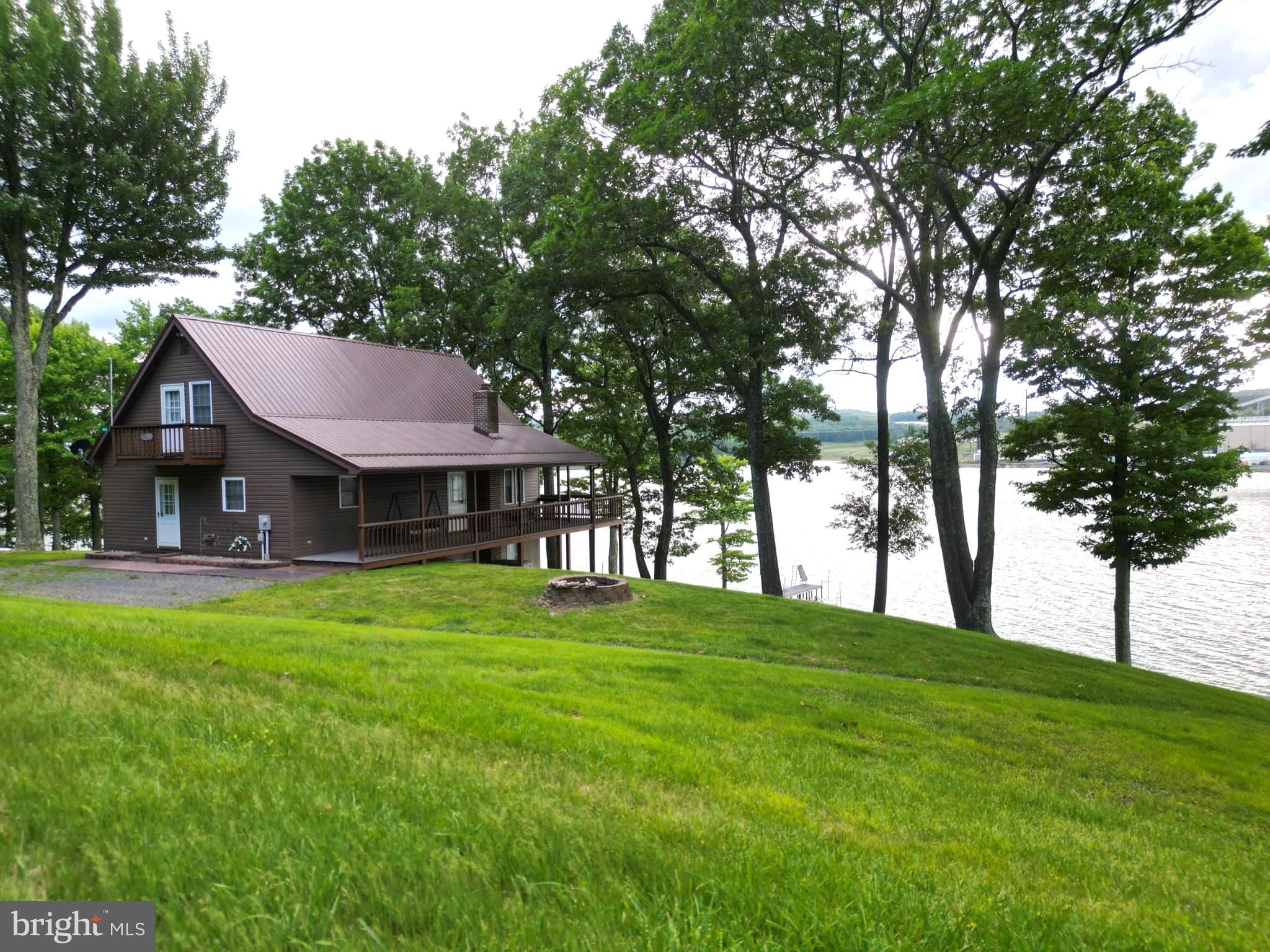 Escape to your very own slice of paradise with this turn key 2-bedroom, 2-bath cabin-style home nestled on a sprawling 4-acre lot. Embrace the serene beauty of nature with over 370 feet of pristine lake frontage, including a private dock with floating docks and a convenient boat launch, situated at the hottest and deepest part of Vepco Lake. This delightful home features a main floor boasting a generous primary bedroom and a spacious open-concept living, dining, and kitchen area, perfect for both relaxing and entertaining. The upper level showcases a loft-style design that can be easily transformed into additional bedrooms to suit your needs. Step outside to enjoy the perfect blend of manicured yard and lush wooded acreage, offering ample space for outdoor activities and exploration. A large detached garage provides ideal storage for boats and summer toys, while the expansive basement, complete with a garage door, offers added convenience and versatility. Properties like this are rare and highly sought after. Don’t miss the opportunity to own this exceptional lakefront retreat—schedule your visit today!