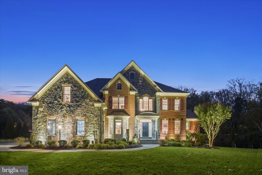 Nestled on a serene cul-de-sac in Ellicott City, 11229 Kinsale Court is a distinguished residence by Winchester Homes, masterfully sited on 0.82 acres backing to preserved land for enduring privacy and picturesque views. With 6 bedrooms, 6 full baths, and 1 half bath, this exceptional home offers three private primary ensuite retreats, refined architectural detailing, and thoughtfully curated upgrades throughout.
A welcoming portico, professional landscaping with graceful weeping willows, and elegant stone, brick, and Hardiplank exterior create striking curb appeal. Slate front and sidewalks, a fully fenced rear yard with two gates, in-ground irrigation, exterior cameras with Guardian app access, and a Generac Guardian generator servicing the main level provide both beauty and peace of mind. The rear oasis features a composite dining deck, stone patio with curved garden walls, and a screened porch—all backing to preserve land with ample space for a future in-ground pool.
Inside, the grand two-story foyer showcases a curved staircase, new chandelier (2026), hardwood floors, and decorative columns that elegantly define the formal living and dining rooms. The formals are appointed with multi-piece crown molding, box moldings, a bay window, custom silhouette blinds, and integrated speakers.
The soaring two-story family room is wrapped in stacked windows and centered around a natural gas fireplace with mantle. Open to the expansive breakfast area and gourmet kitchen, this space is designed for both everyday living and grand entertaining. The oversized kitchen is a chef’s dream, featuring a six-burner gas cook station with downdraft on the island, granite countertops, wrap-around cabinetry, planning desk, walk-in pantry with customized pull-out drawers, stainless steel appliances, new dishwasher (2022), new double wall oven (2025), and fresh paint (2026). Filtered water services the sink and refrigerator. An adjacent secondary back stair and second main-level laundry enhance convenience.
The main-level primary suite (one of three) offers a private retreat with dual organized closets, a spa bath with clerestory windows, and integrated speakers—ideal for multi-generational living or luxurious guest accommodations.
Upstairs, all bedrooms feature hardwood flooring. The upper-level primary suite (two of three) impresses with a tray ceiling, sitting area, sweeping bay window, oversized dressing closet with window, second walk-in closet, and proximity to the hall laundry center with utility sink and secondary stair. The primary bath showcases separate vanities, new quartz countertops, new faucets, and lighting (2026.)  A walk-in shower, corner soaking tub, and dual filtered water stations enhance the bath. Additional upper-level bedrooms include a private ensuite and two generously sized rooms, one ideal as a study.
The finished walk-out lower level is designed for entertaining and extended living, with full daylight windows and engineered wood floors. The recreation and media area flows seamlessly to the dining space and an impressive wet bar with full back bar, wrap-around seating, full refrigerator, stainless sink, ceramic tile flooring, and atrium access to the patio and screened porch. Two full baths serve this level. The third primary ensuite—currently used as an exercise room—features a walk-in closet and private bath. A flexible bonus room with French doors and built-in storage offers endless possibilities.
Additional highlights include two laundry centers, natural gas heating and hot water, central AC, interior speaker system, purified and filtered water service by National Water, proactive pest control, and an epoxy-finished three-car side-loading garage with built-in shelving.   An extraordinary offering combining timeless elegance, modern functionality, and serene privacy—11229 Kinsale Court is luxury living at its finest.